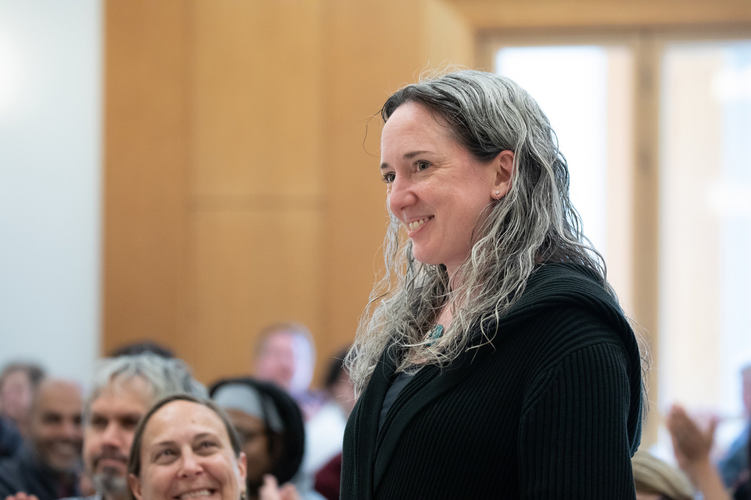 A woman standing up in a crowd in a room