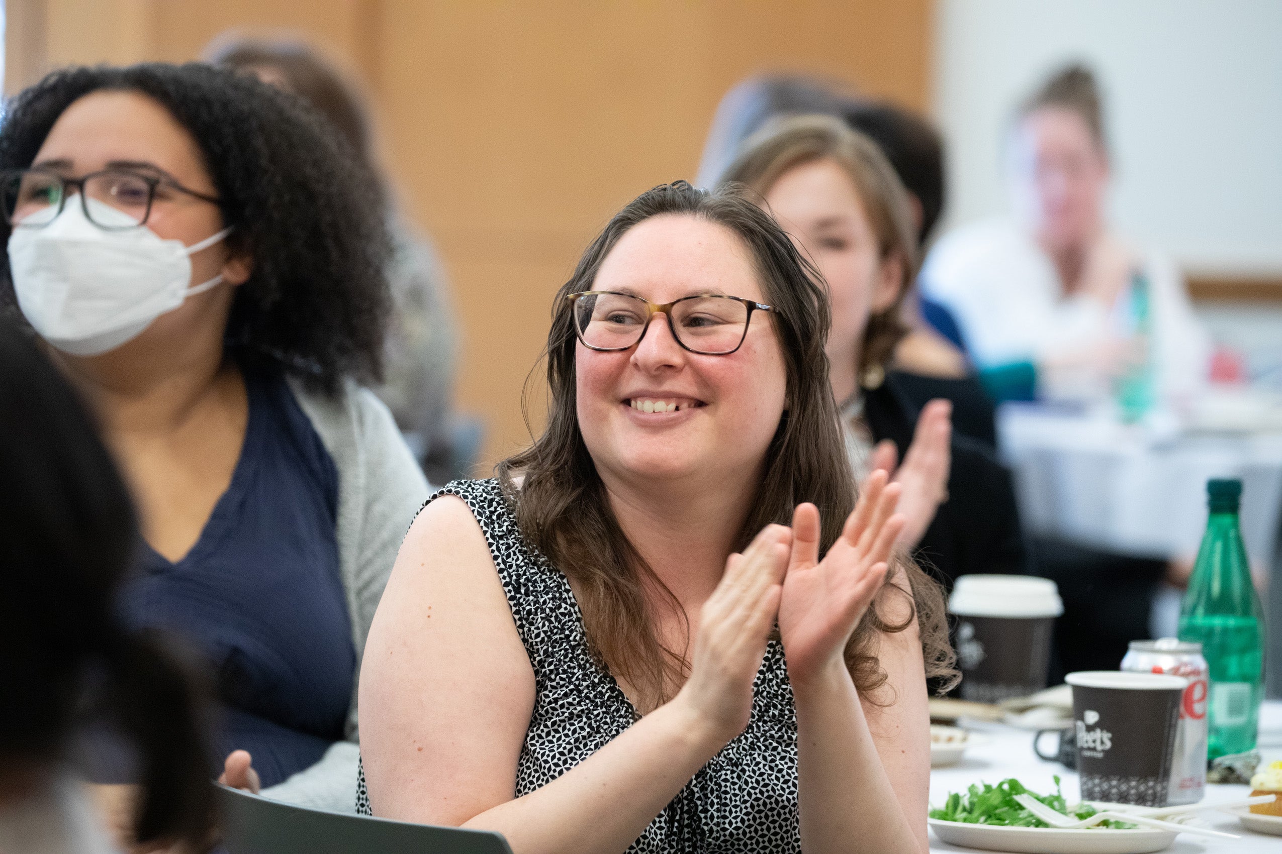 A woman sitting at a table clapping