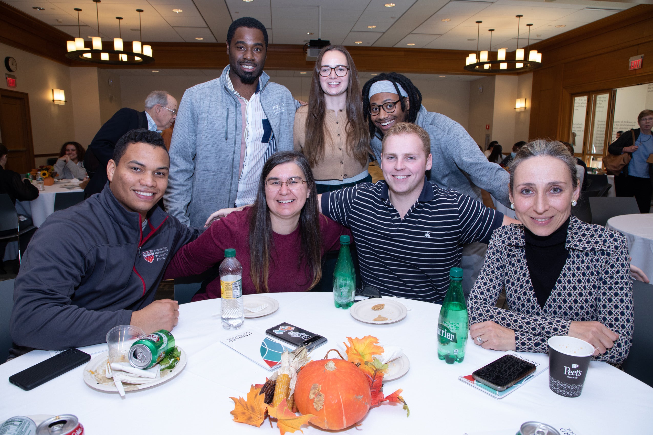 A group of four men and two women pose for a group photo at a table.