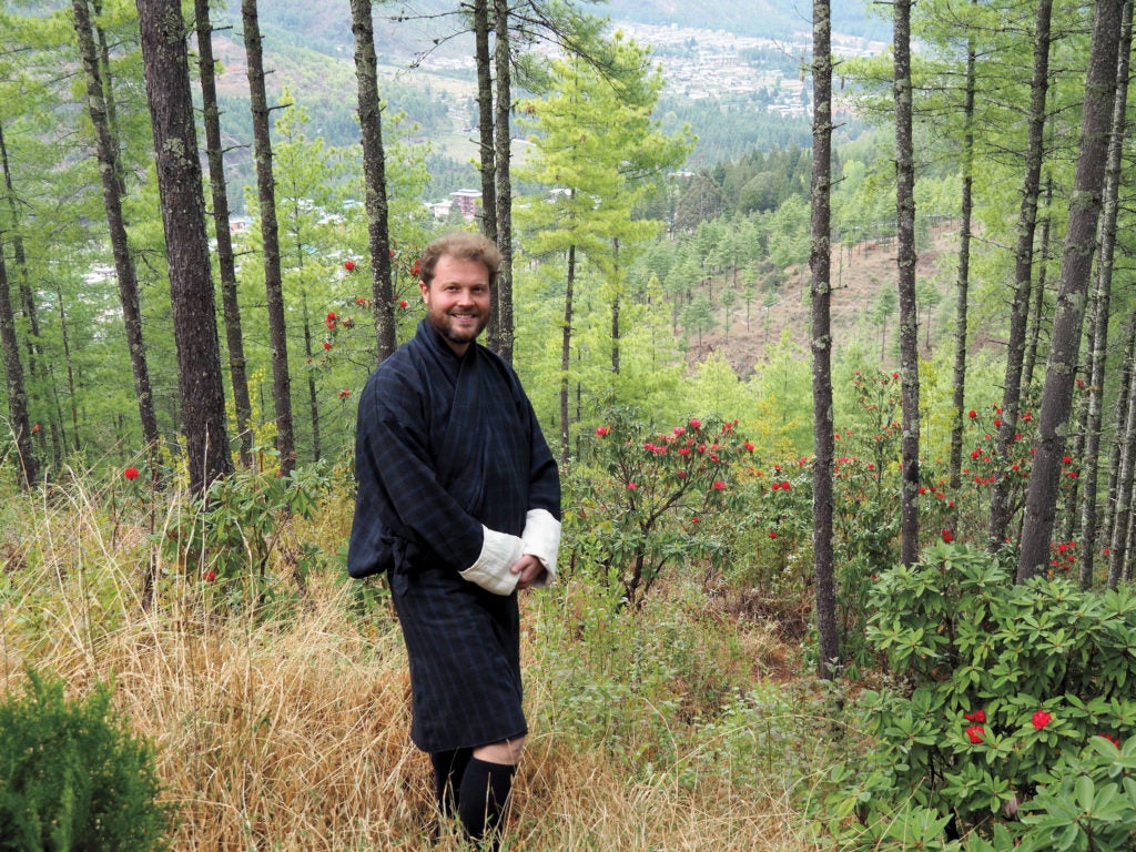 Man standing in a field near a forest
