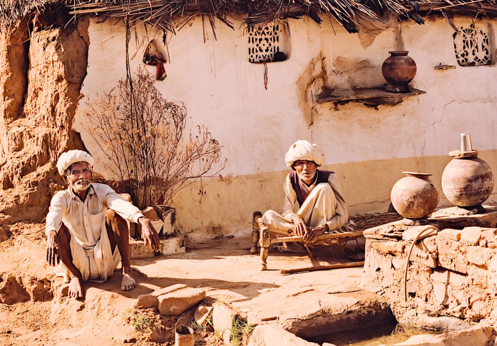 two men squatting on the ground near earth ware