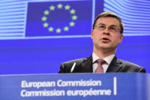 Valdis Dombrovskis stands behind a podium at a European Commission event.