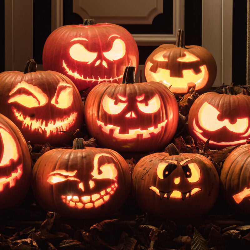 Several illuminated jack-o-lanterns in front of a house.