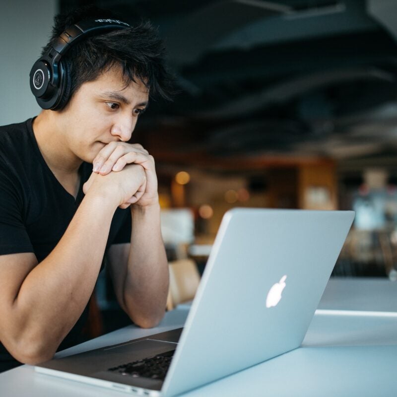 A man with headphones on watching a video on his computer.