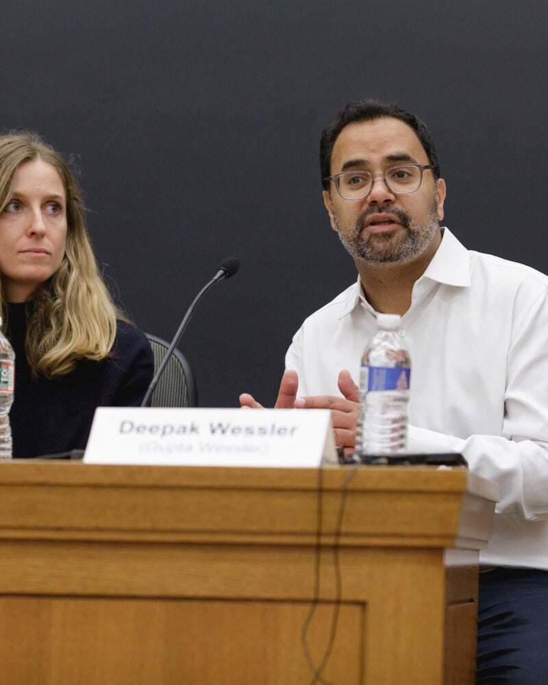 A panelist in a classroom speaks as another listens