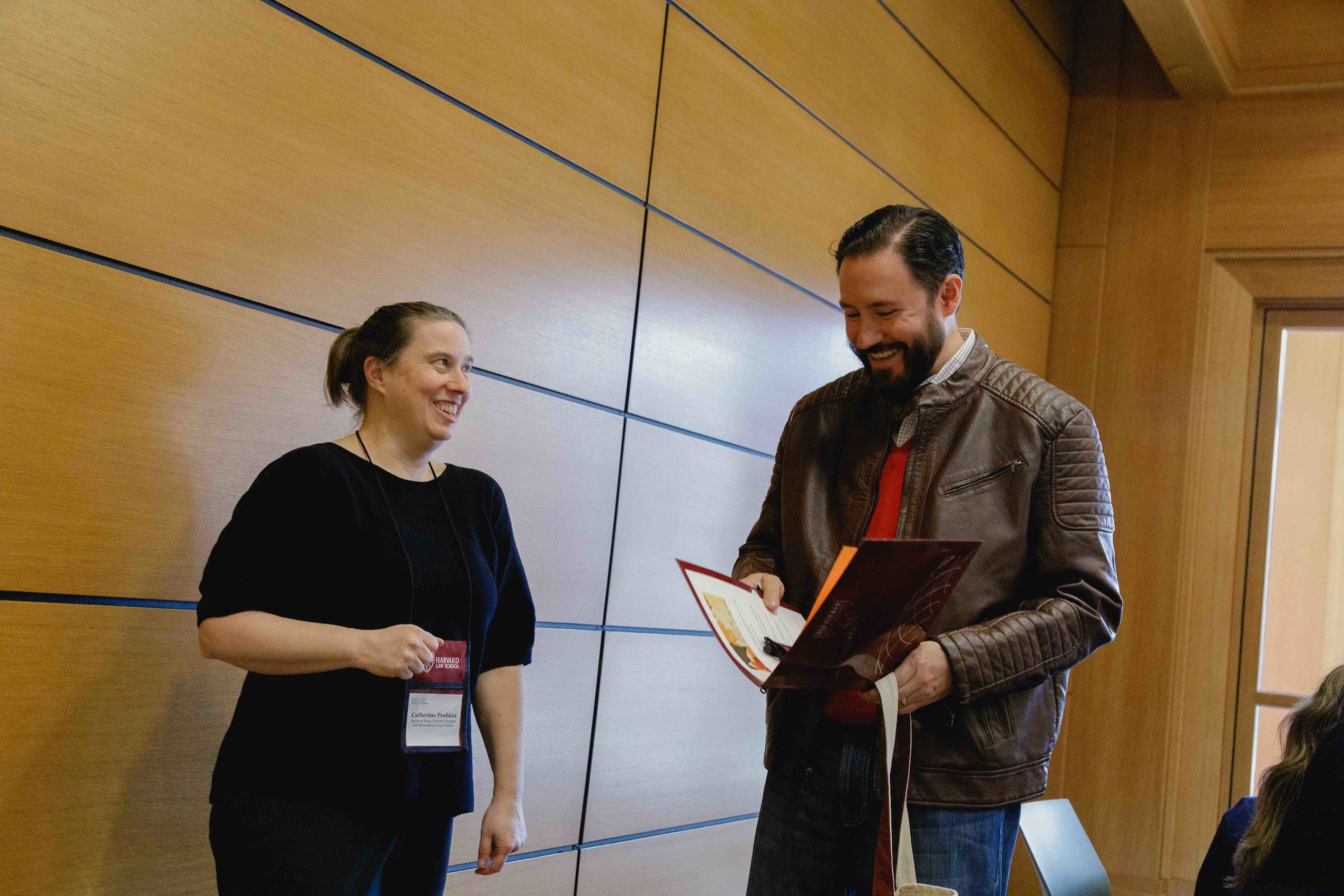 A woman talking to a man holding a folder of information