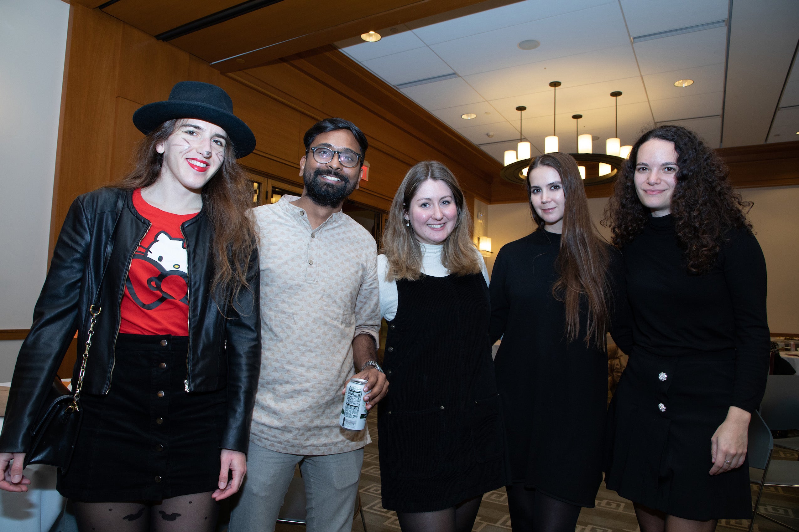 A group of five poses for a photo one students is wearing a black hat and cat t-shirt