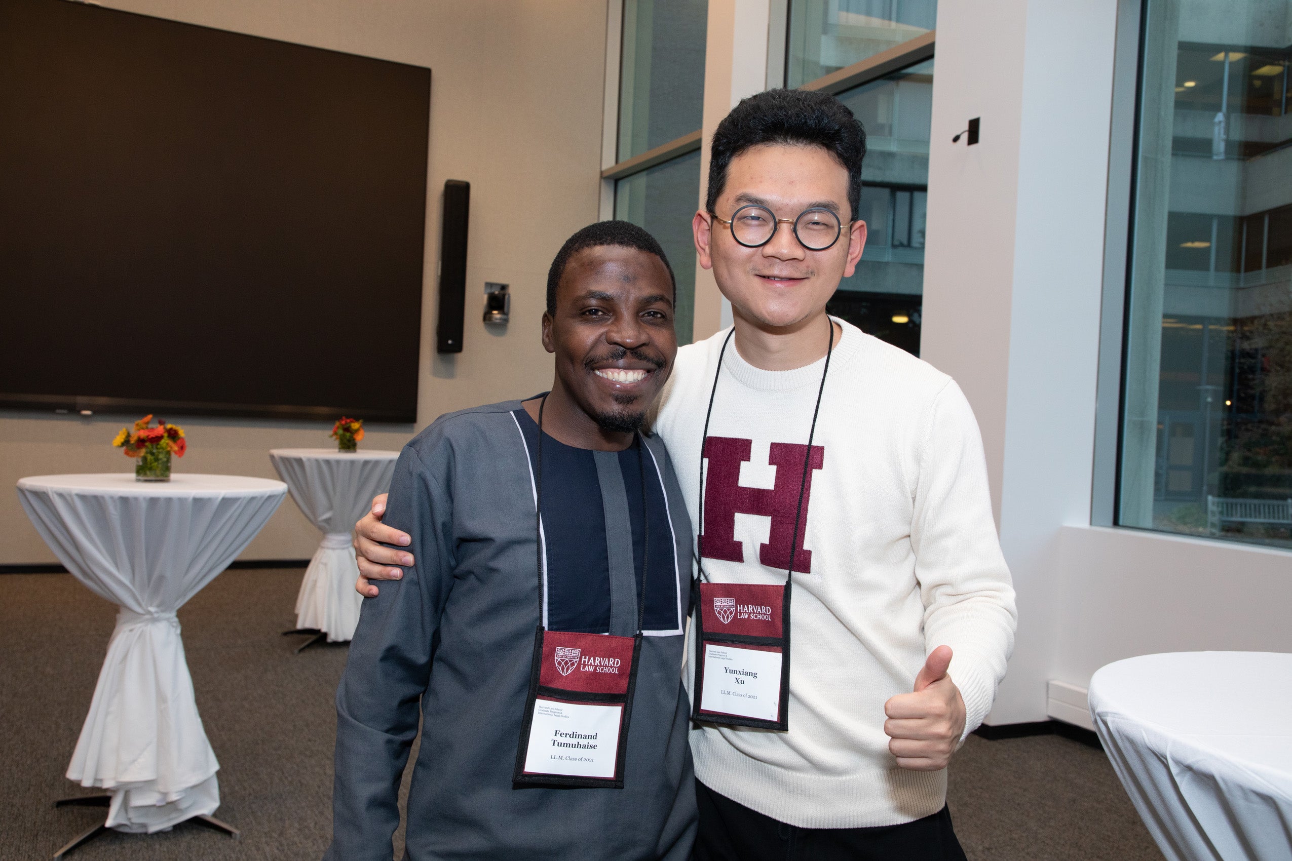 Two men wearing Harvard Law School name badges pose for the camera at an event