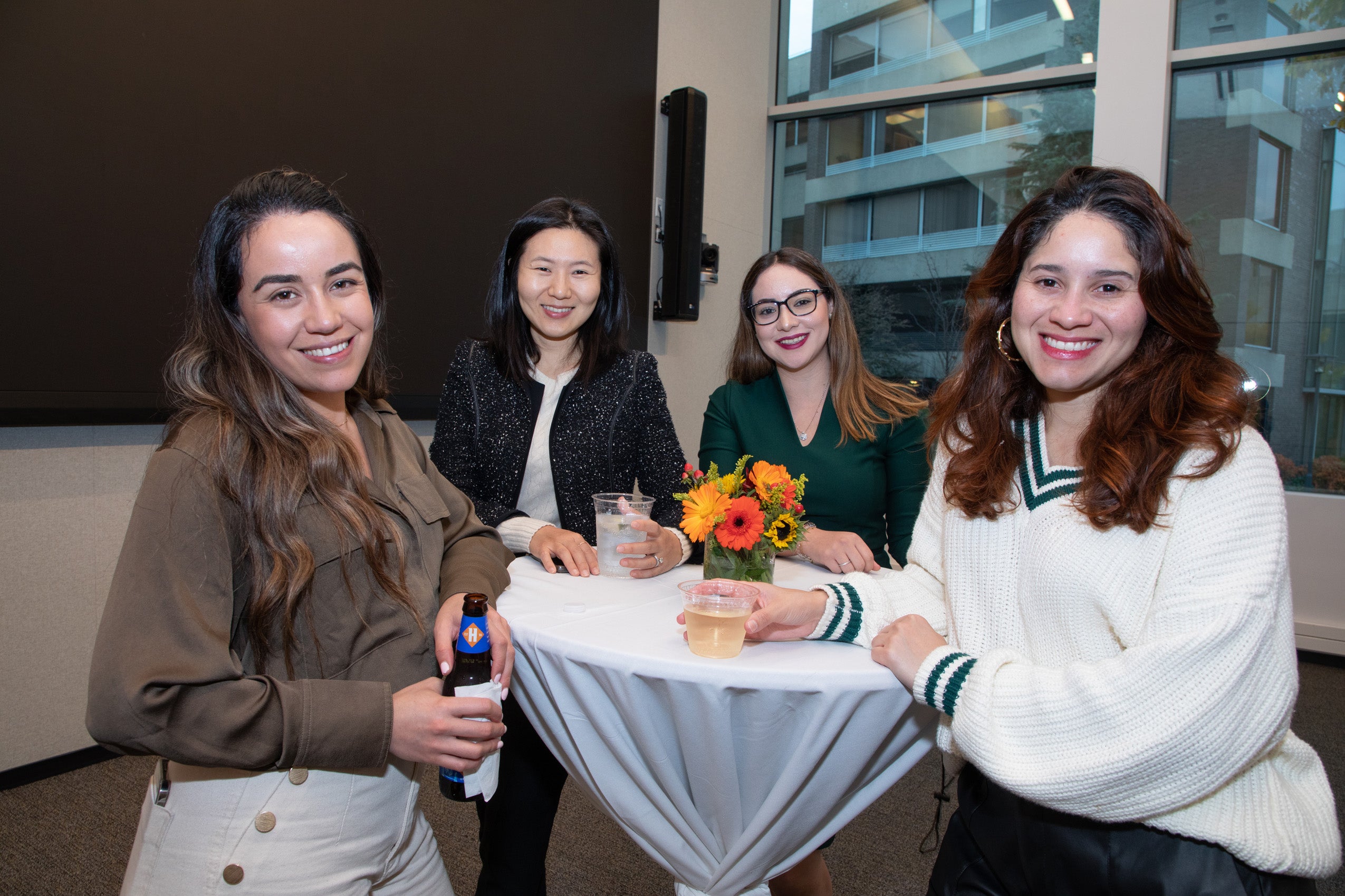 Four women gather around a hightop table at a reception