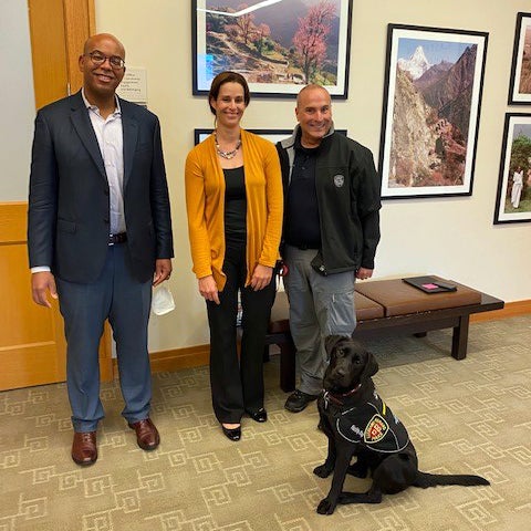 Deans Stephen Ball and Jessica Soban pose with Sasha, Harvard's community engagement dog, and HUPD Officer Steven Fumicello.