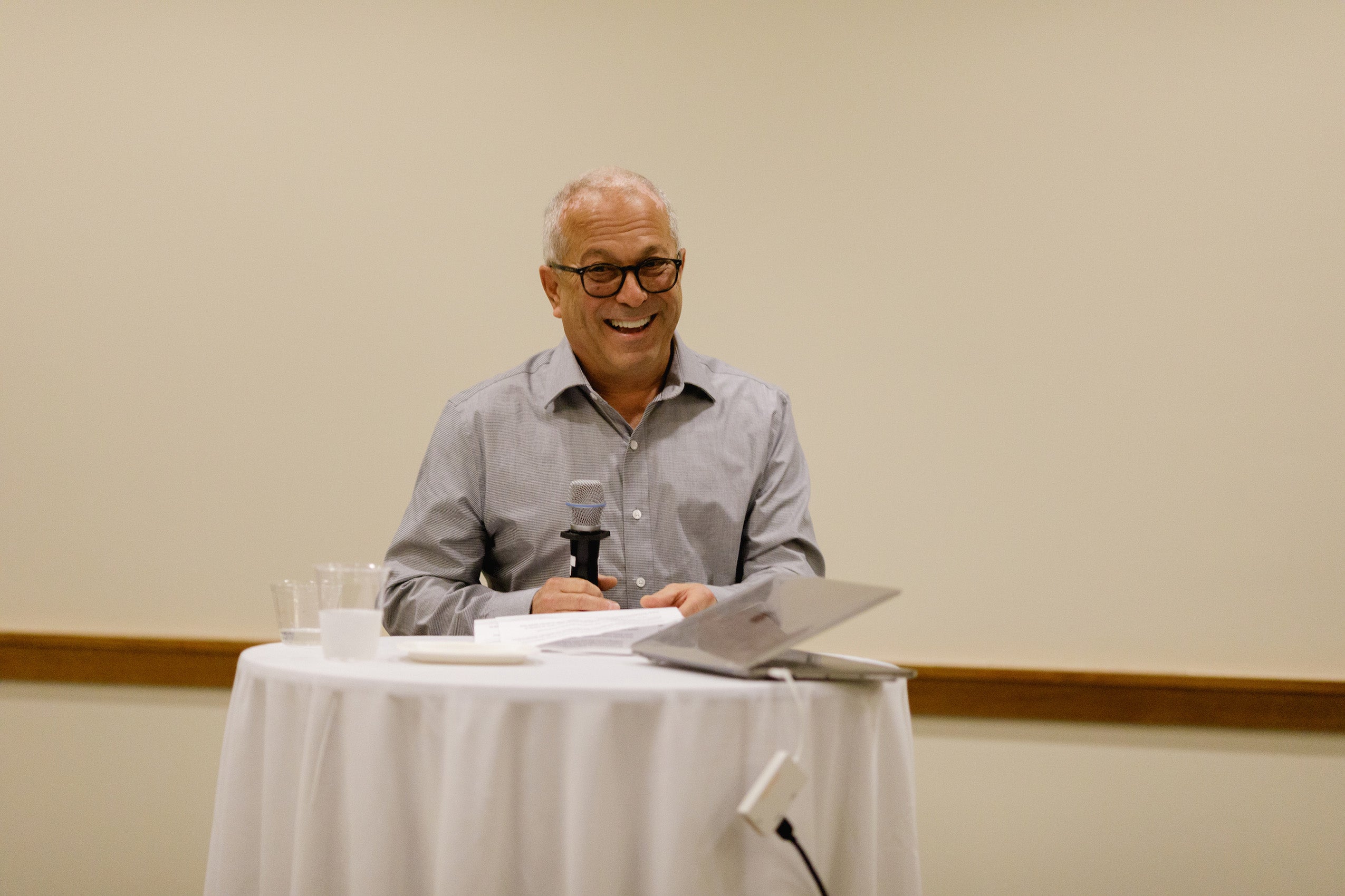 Man standing at a table holding a microphone