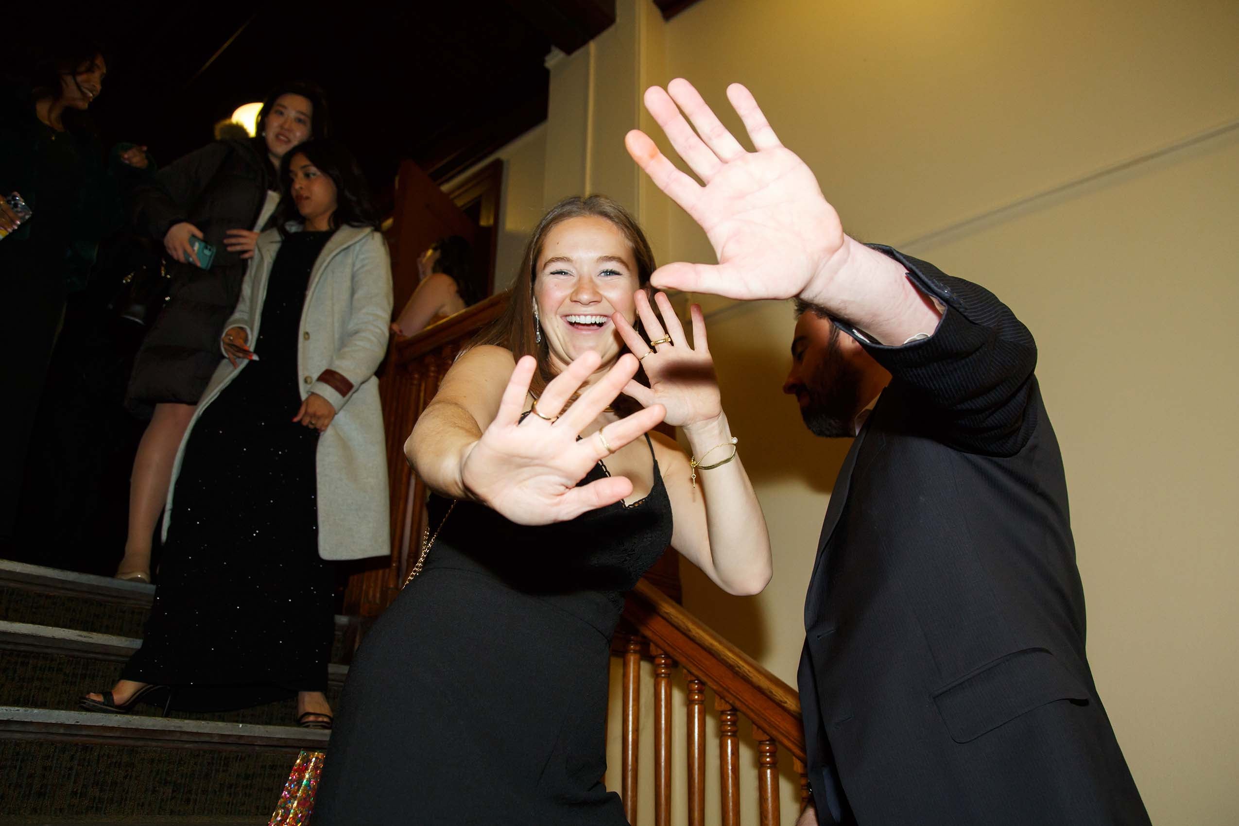 A man and woman standing on stairs, playfully covering their faces from the camera.