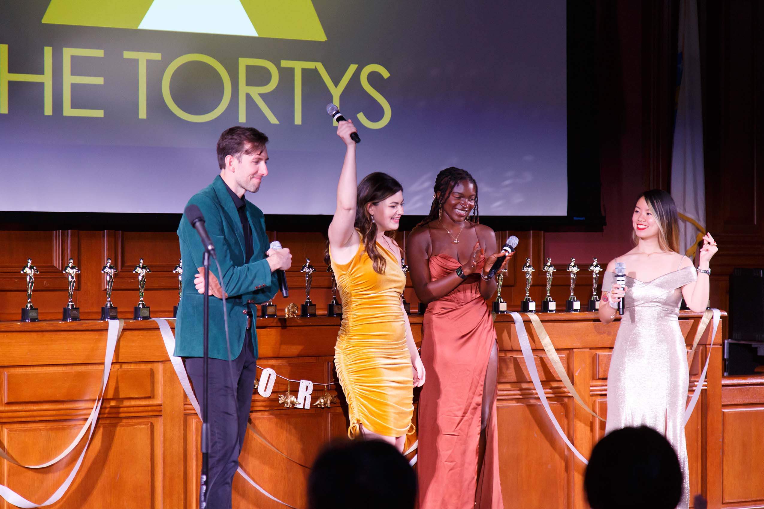 A group of students wearing formal attire stands on stage celebrating a win.