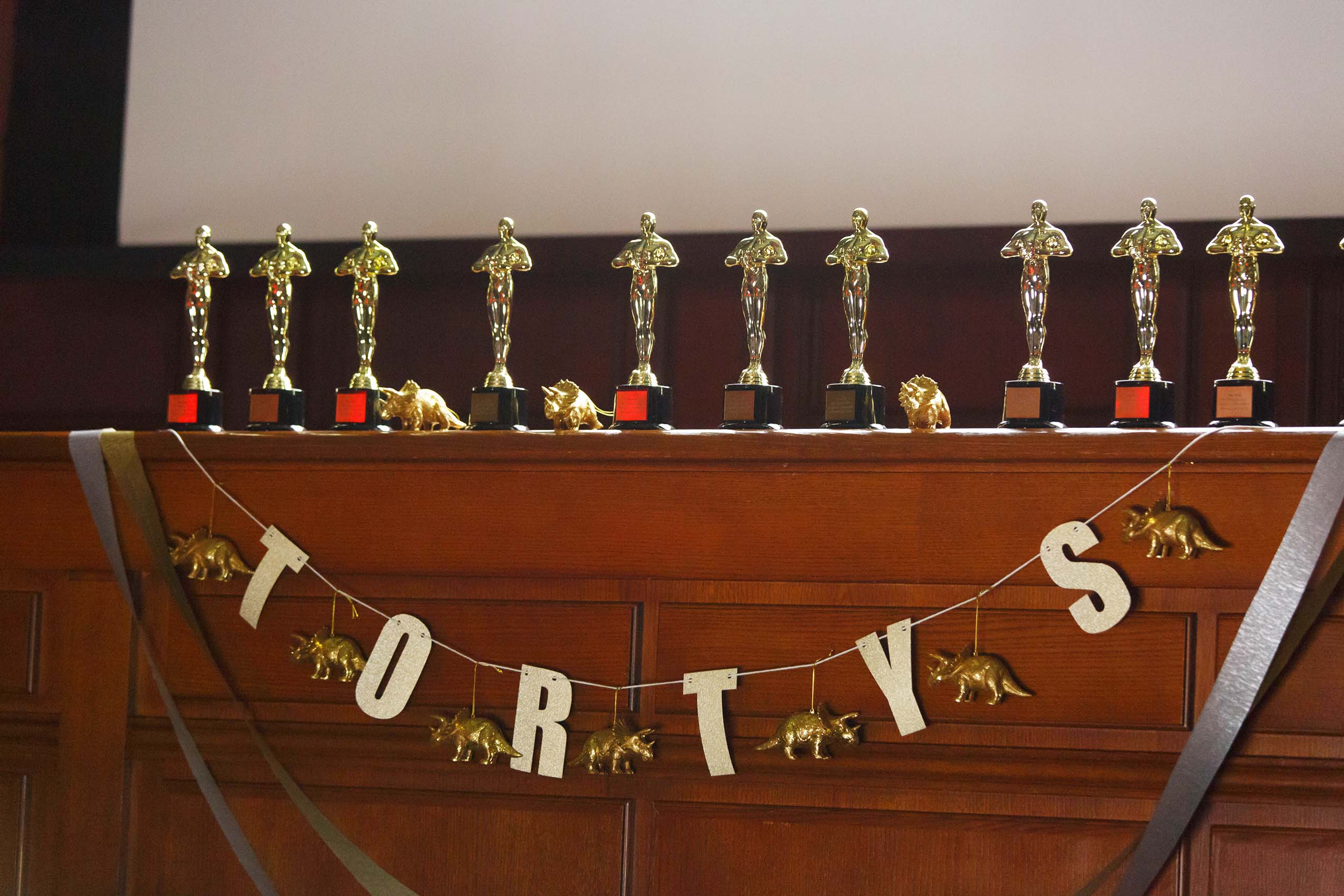 A row of golden awards on a ledge, a sign under them says
