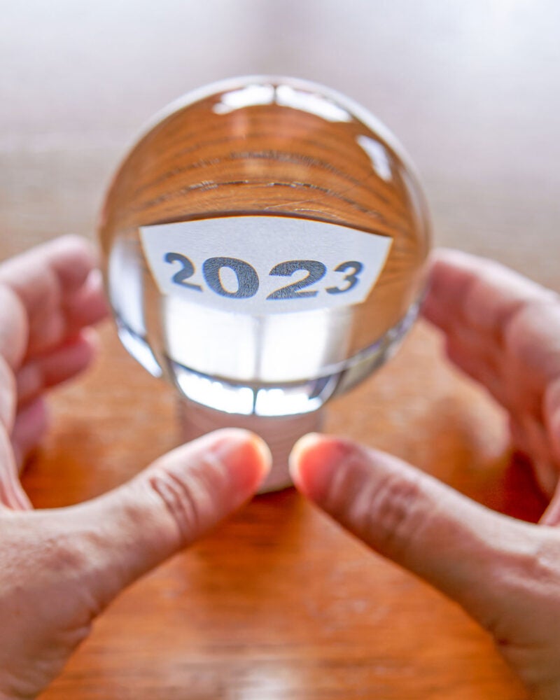 Two hands holding a clear glass ball with the year 2023 inside.