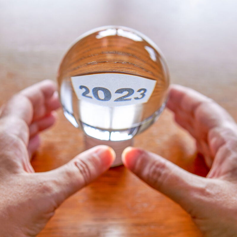 Two hands holding a clear glass ball with the year 2023 inside.