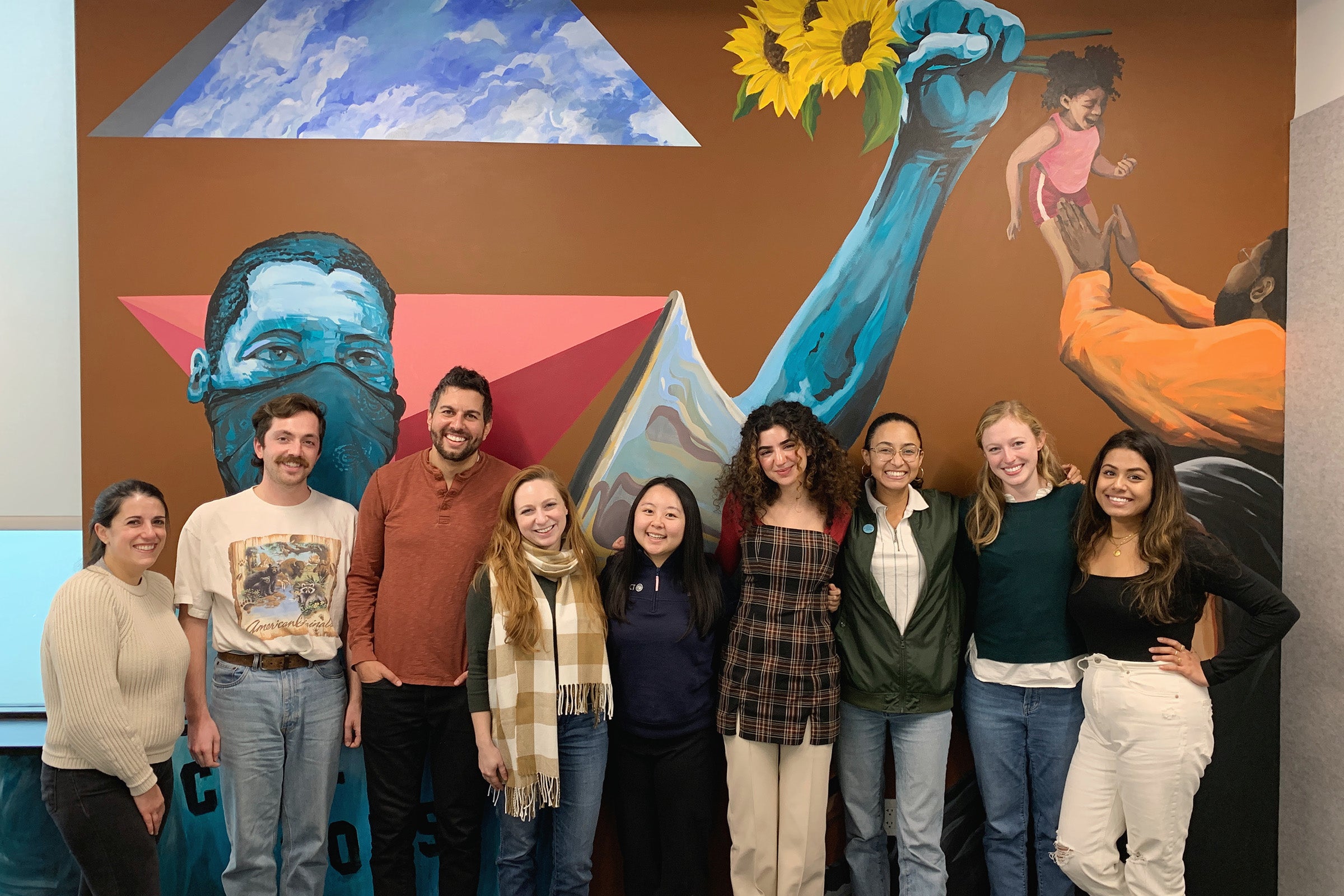Criminal Justice Appellate Clinic students and directors pose in front of a mural at the MacArthur Justice Center in Washington, DC.