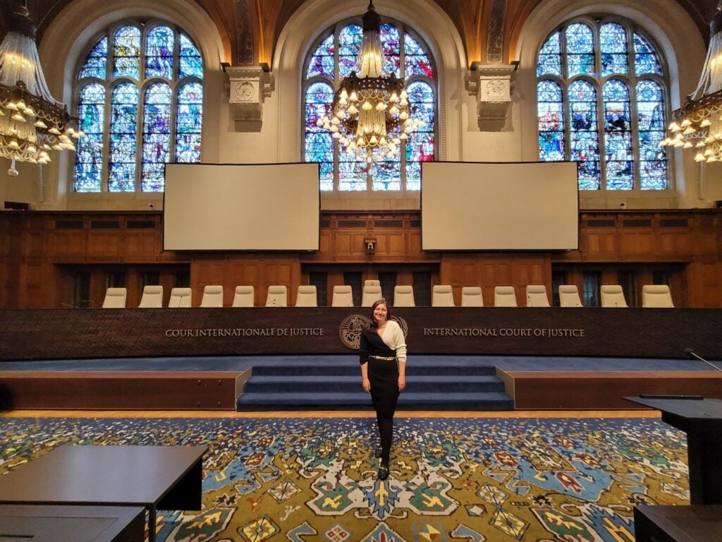 Ennely Medina poses in the front of the empty ICC courtroom