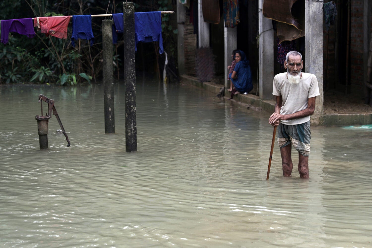 A man with a cane walking through floodwaters in Bangladesh.