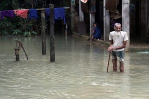 A man with a cane walking through floodwaters in Bangladesh.