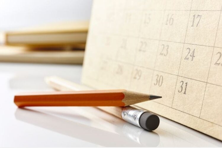 A pencil resting against a calendar.