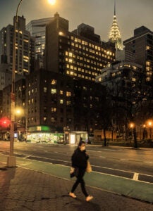 night city scene woman walking along a sidewalk wearing a mask during Coronavirus emergency