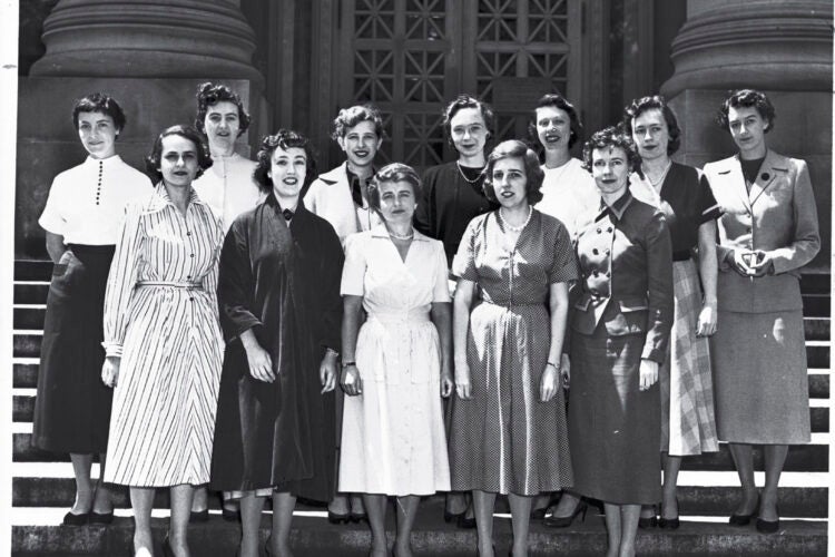 A group of women standing in two rows on the steps of a campus building