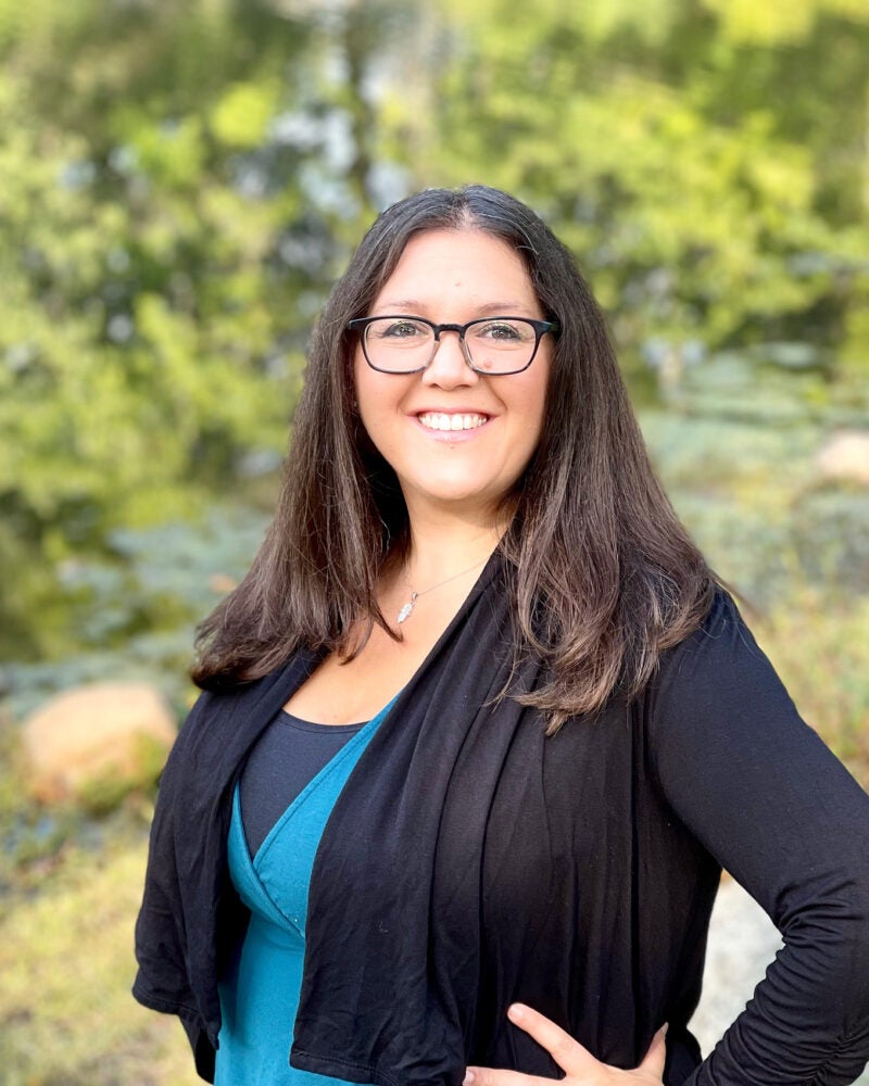 Portrait of a woman with long black hair outside near a stream