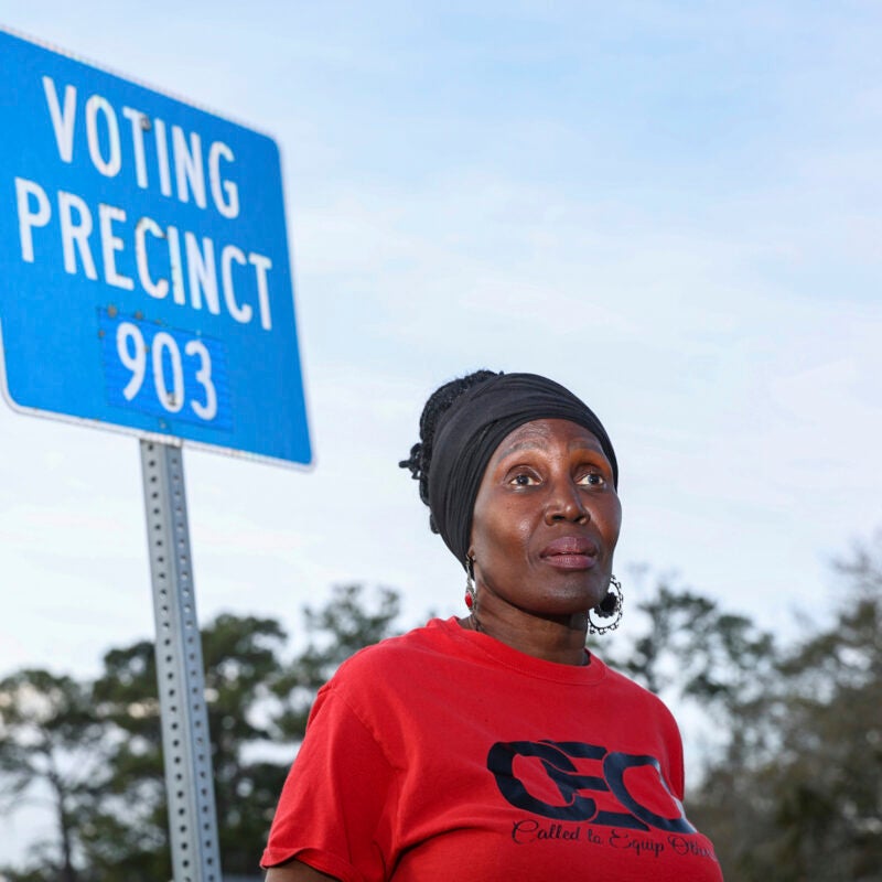 Voting rights activist Rosemary McCoy stands in front of a blue sign that reads 
