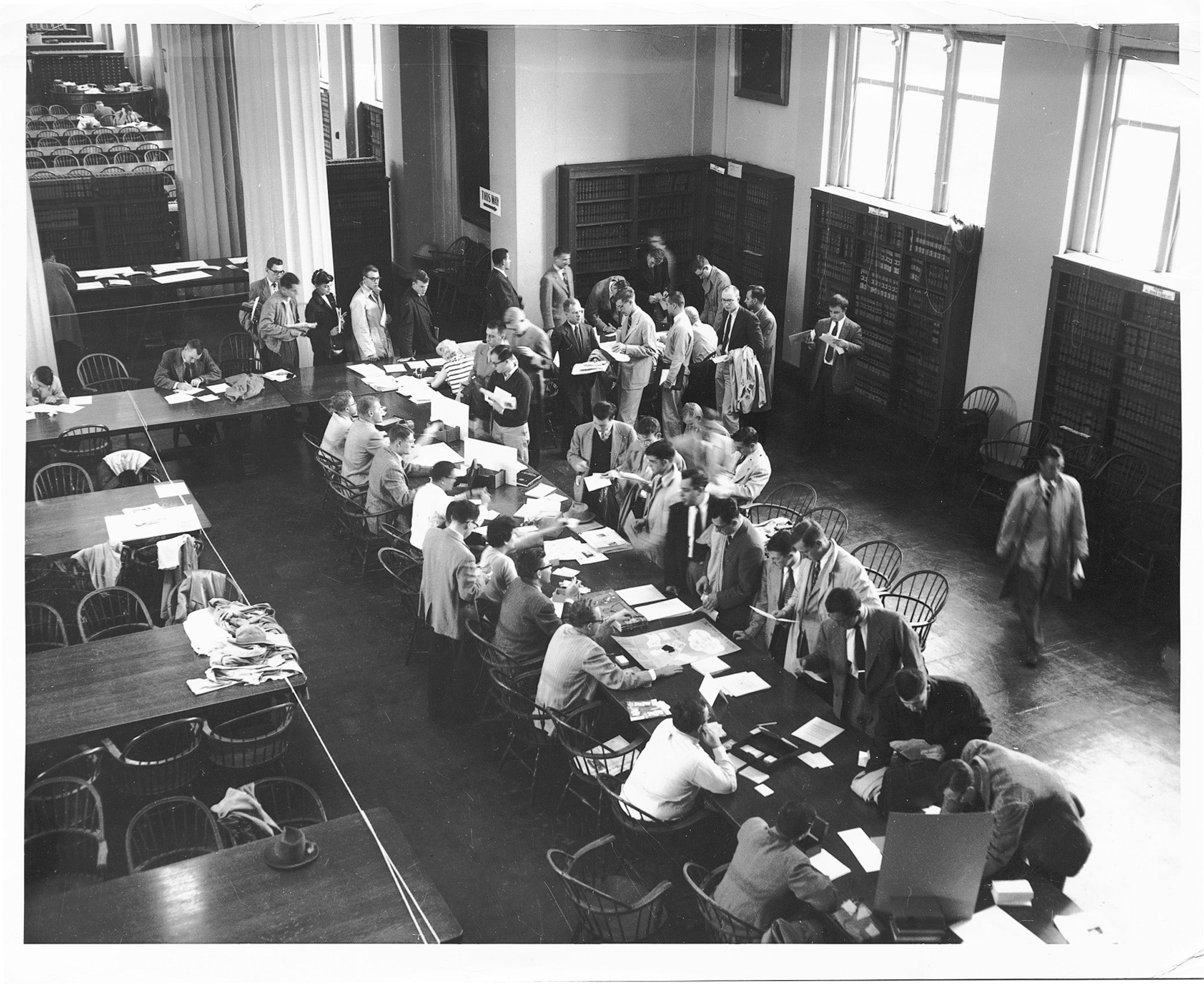 One women in a long line of men during registration in the a library.