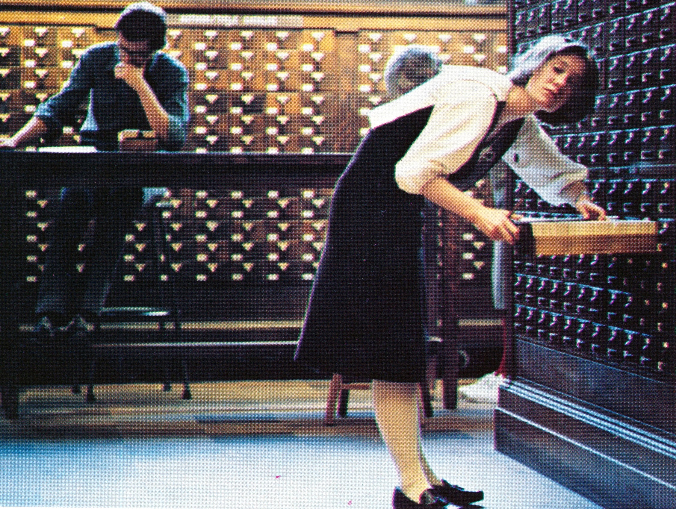 A women looks up as she is going through a library card catalogue