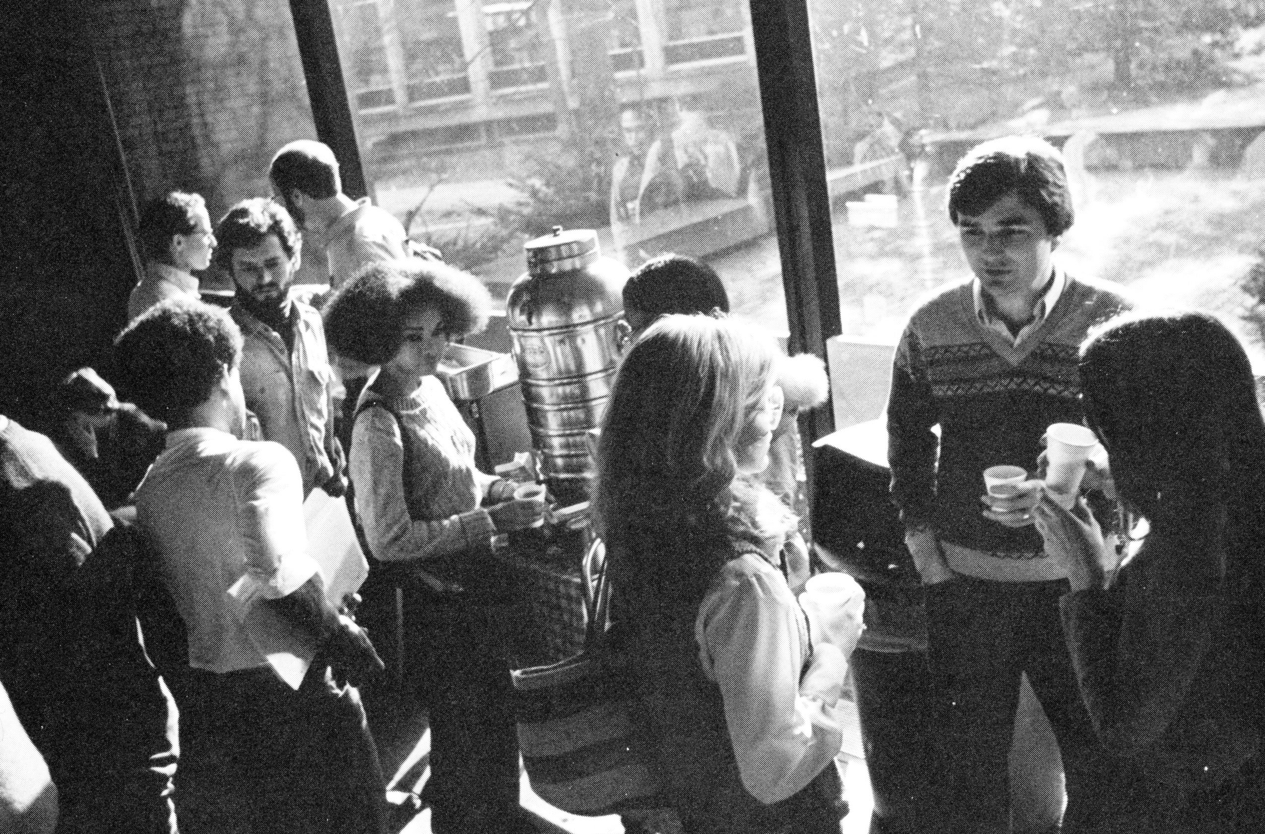 A group of students men and women gather for a coffee break