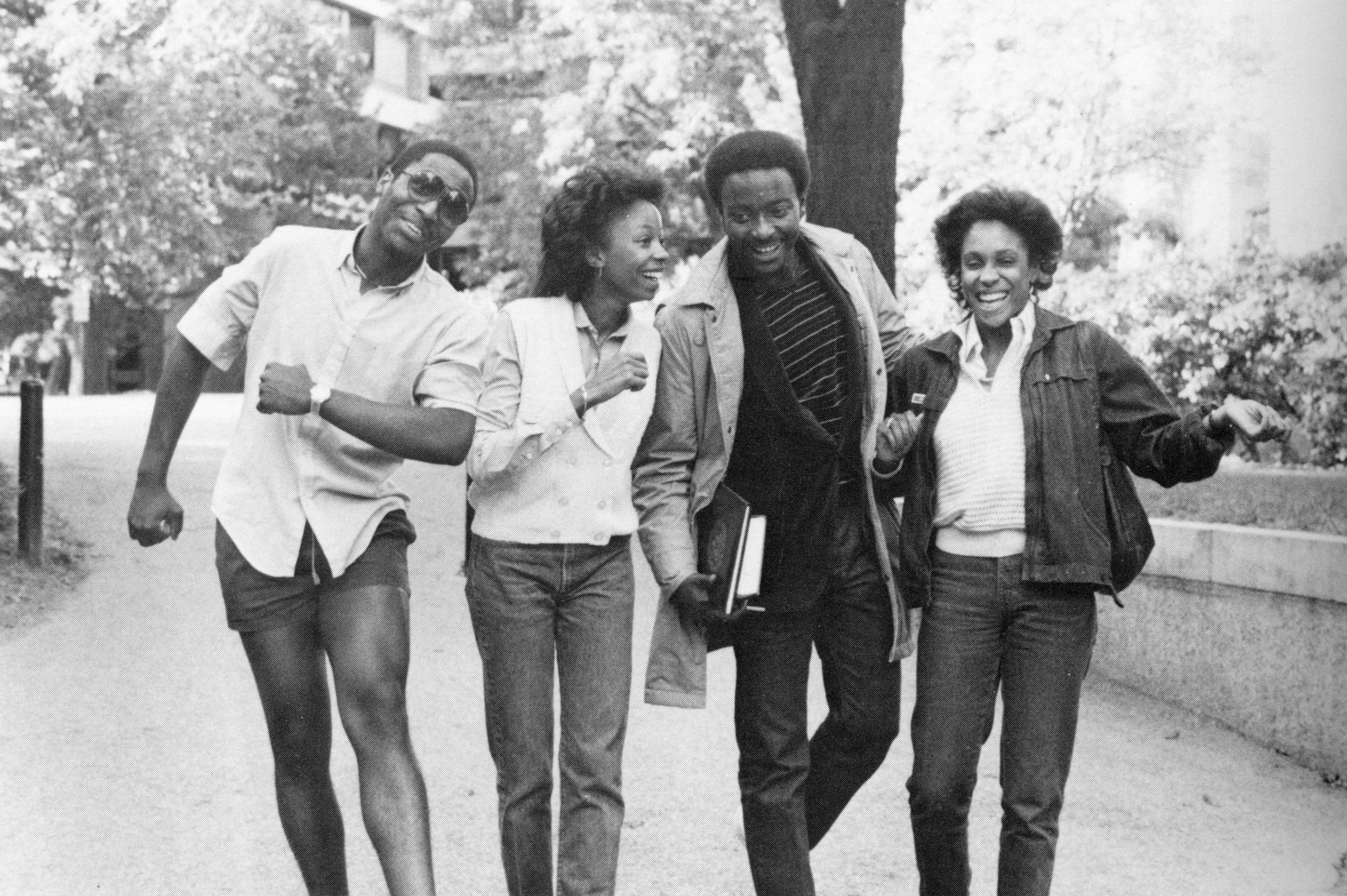 Four students joyfully walking on campus