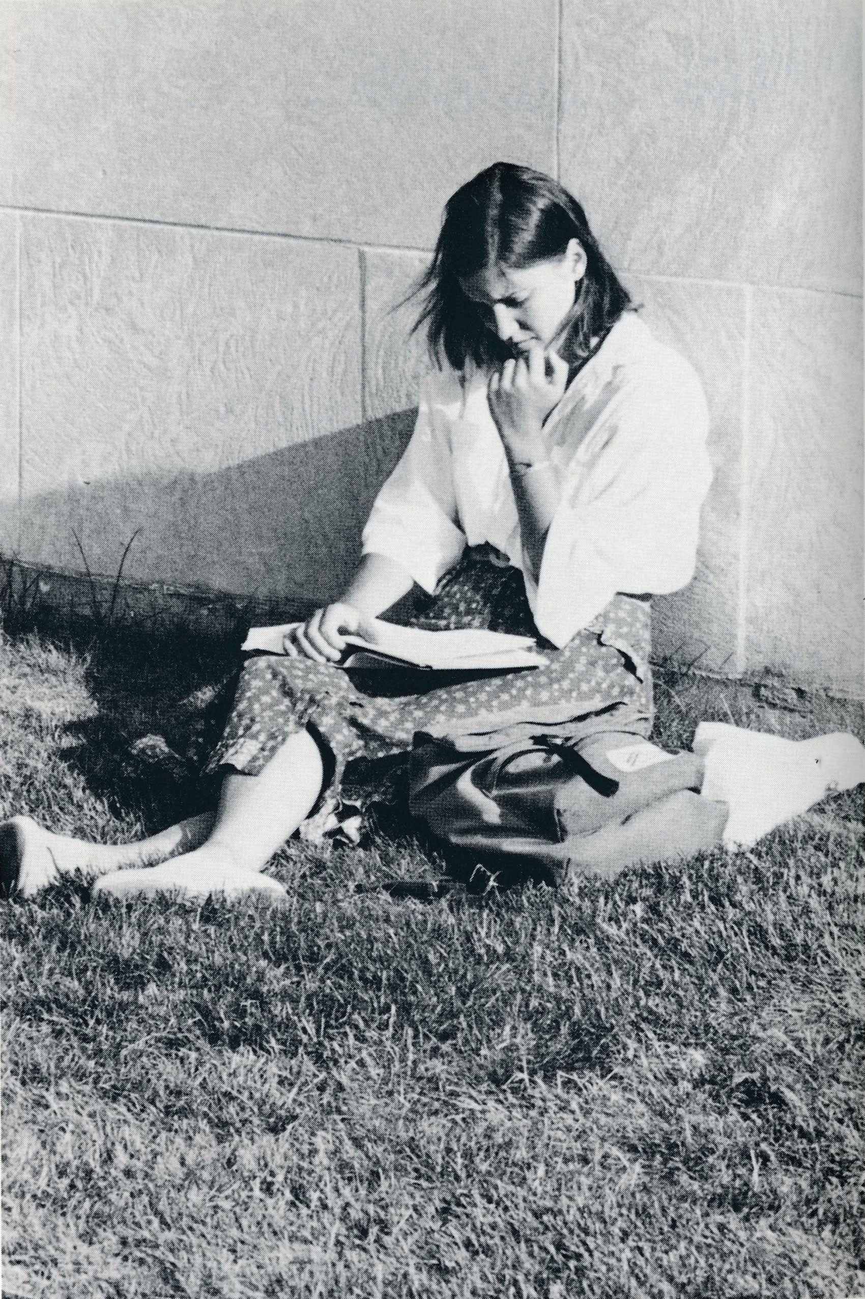 A woman sitting outside on the grass studying