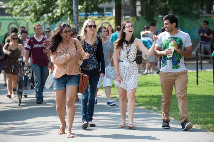 A group of students walk happily along a path on campus