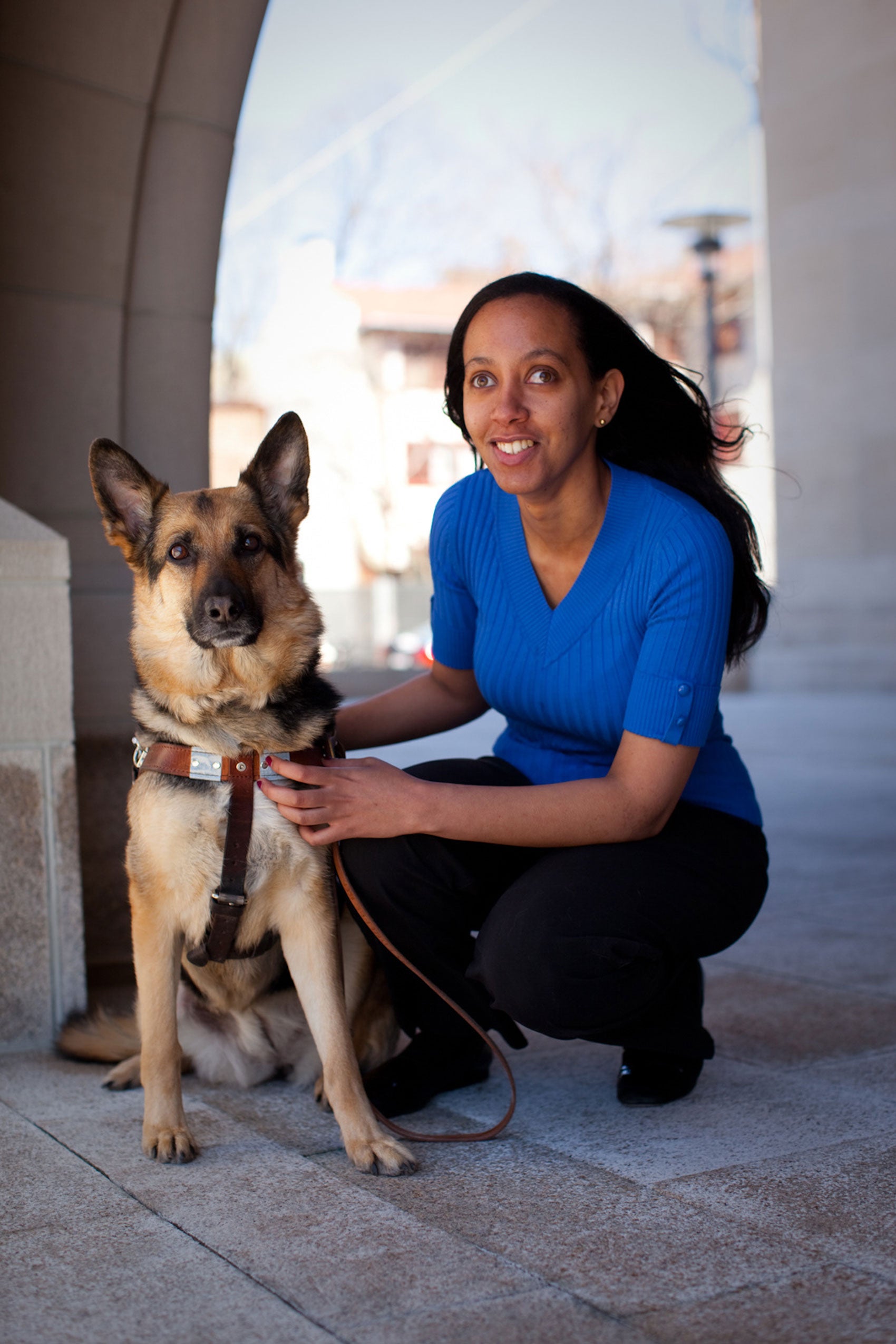 A woman sits next to her seeing eye dog on campus