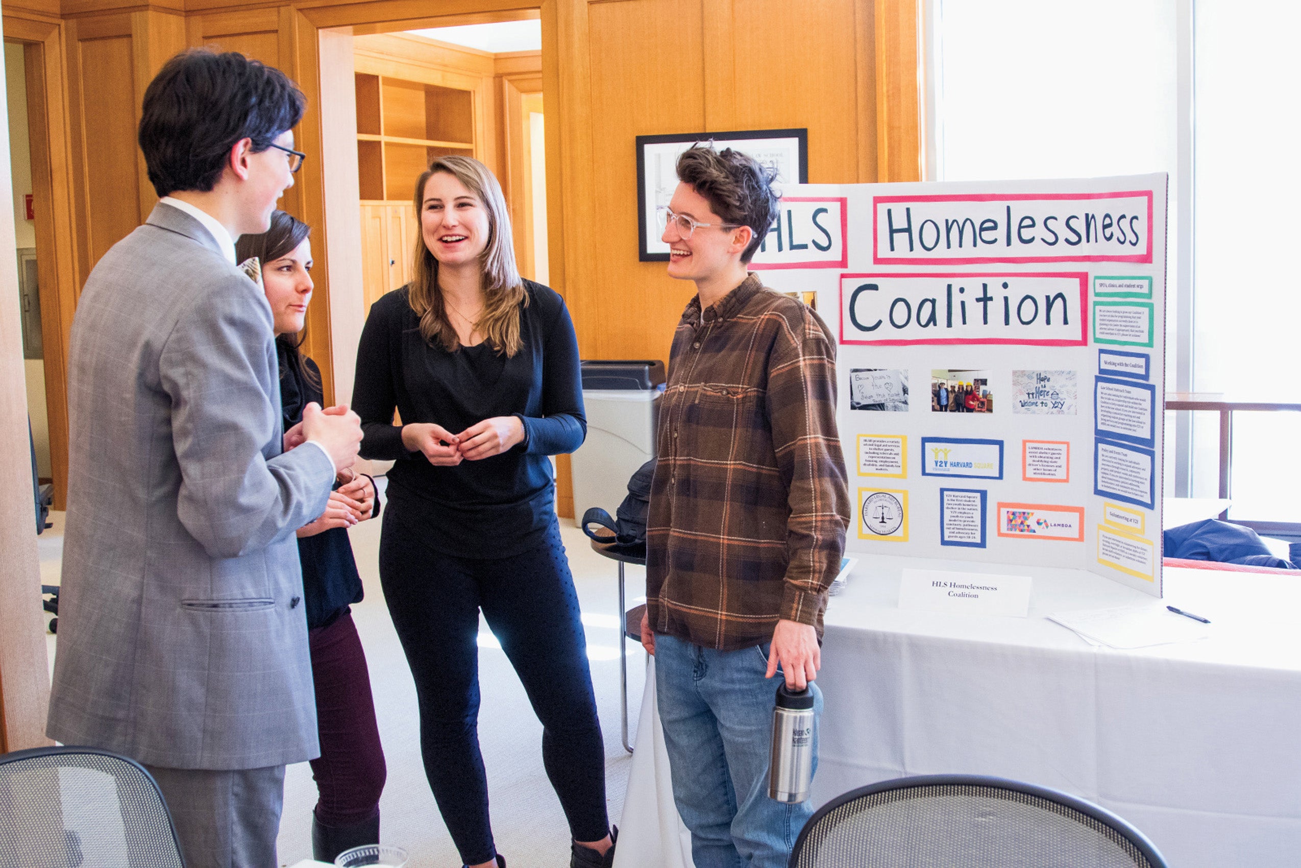 Students chat at a student organization fair a post for the Homelssness coalition is in the background