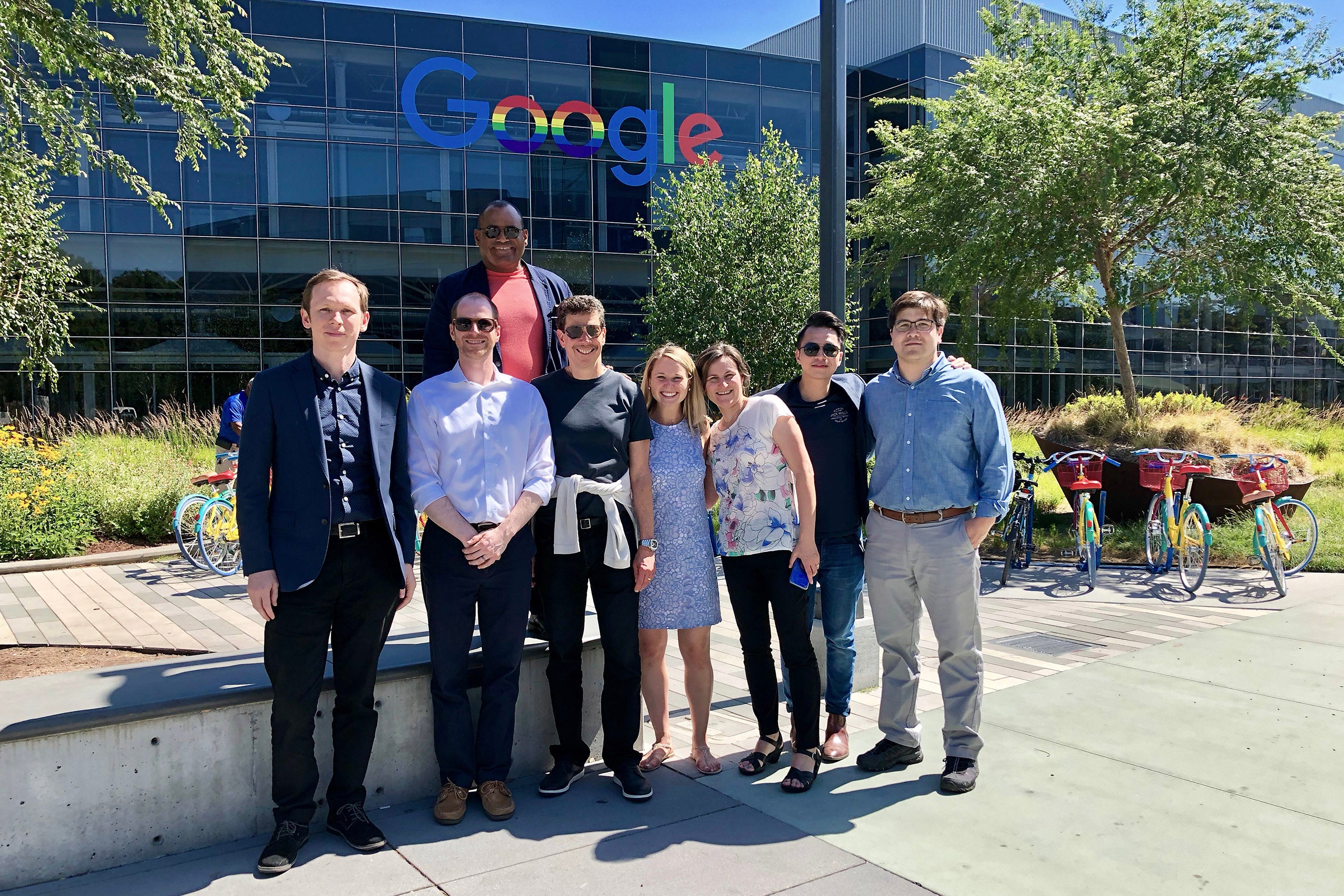 Group of eight people standing in front a building with the Google logo on it.