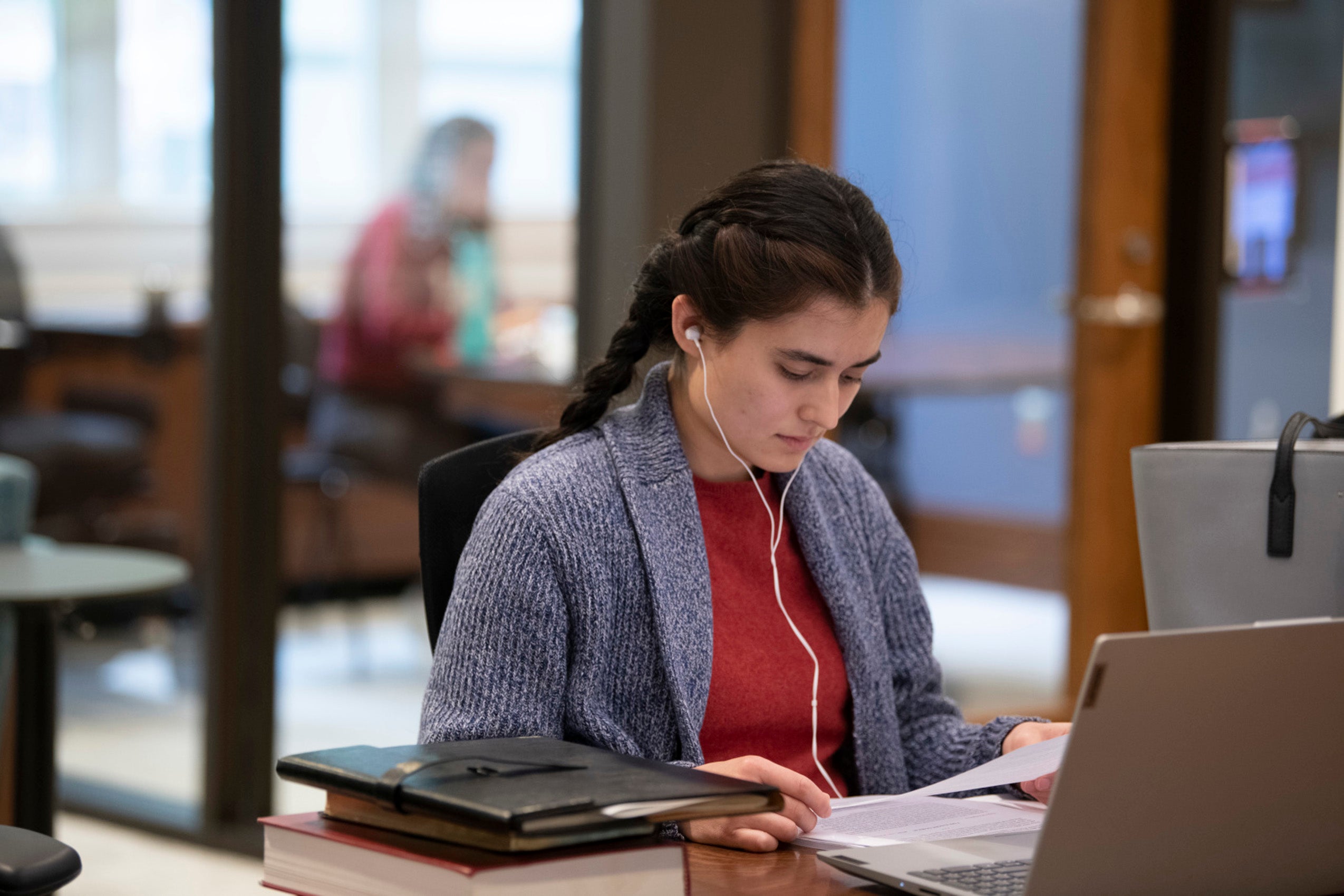 a woman sitting at her computer studying and listening to with headphones