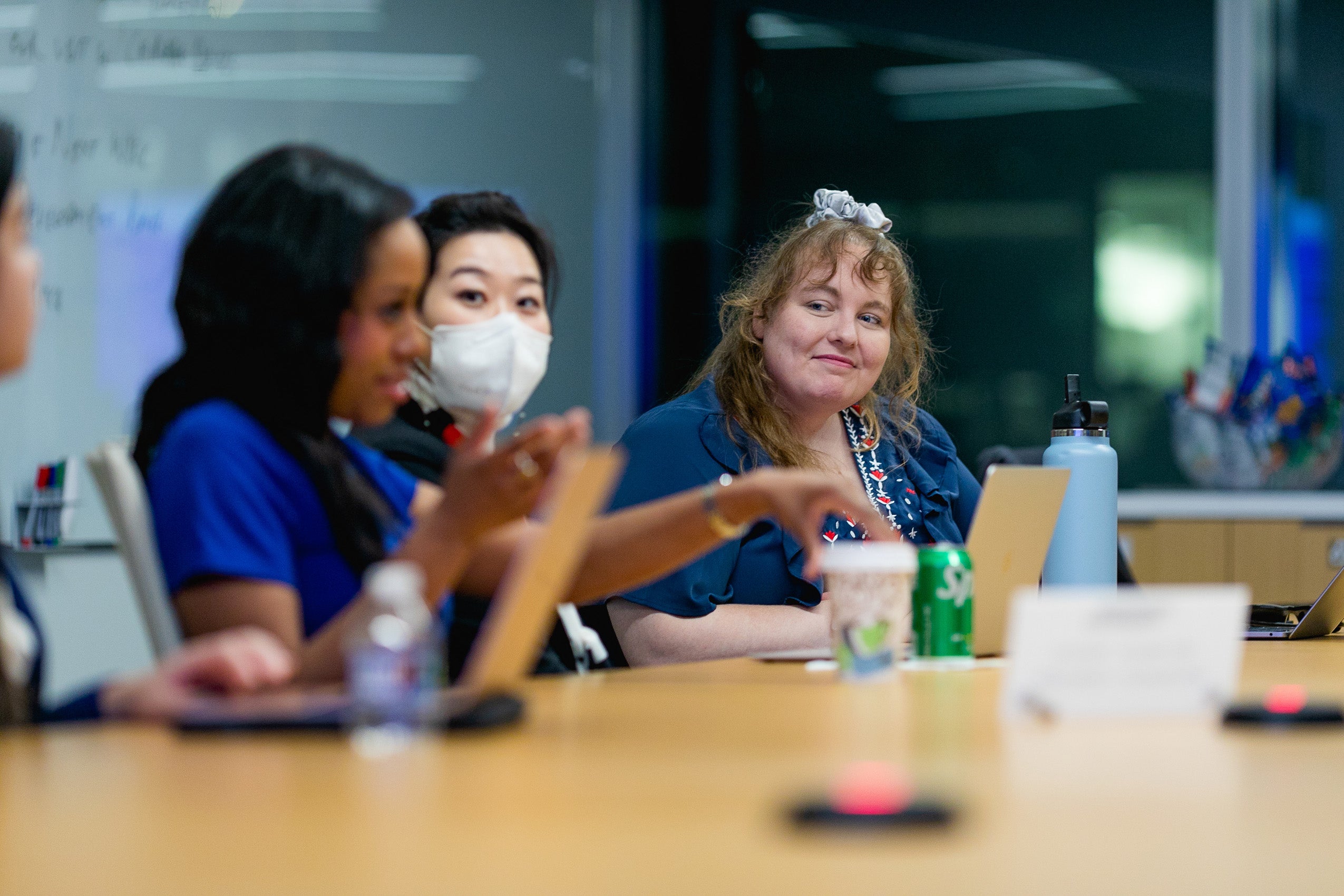 A woman smiles as she listens to others at the table make a point