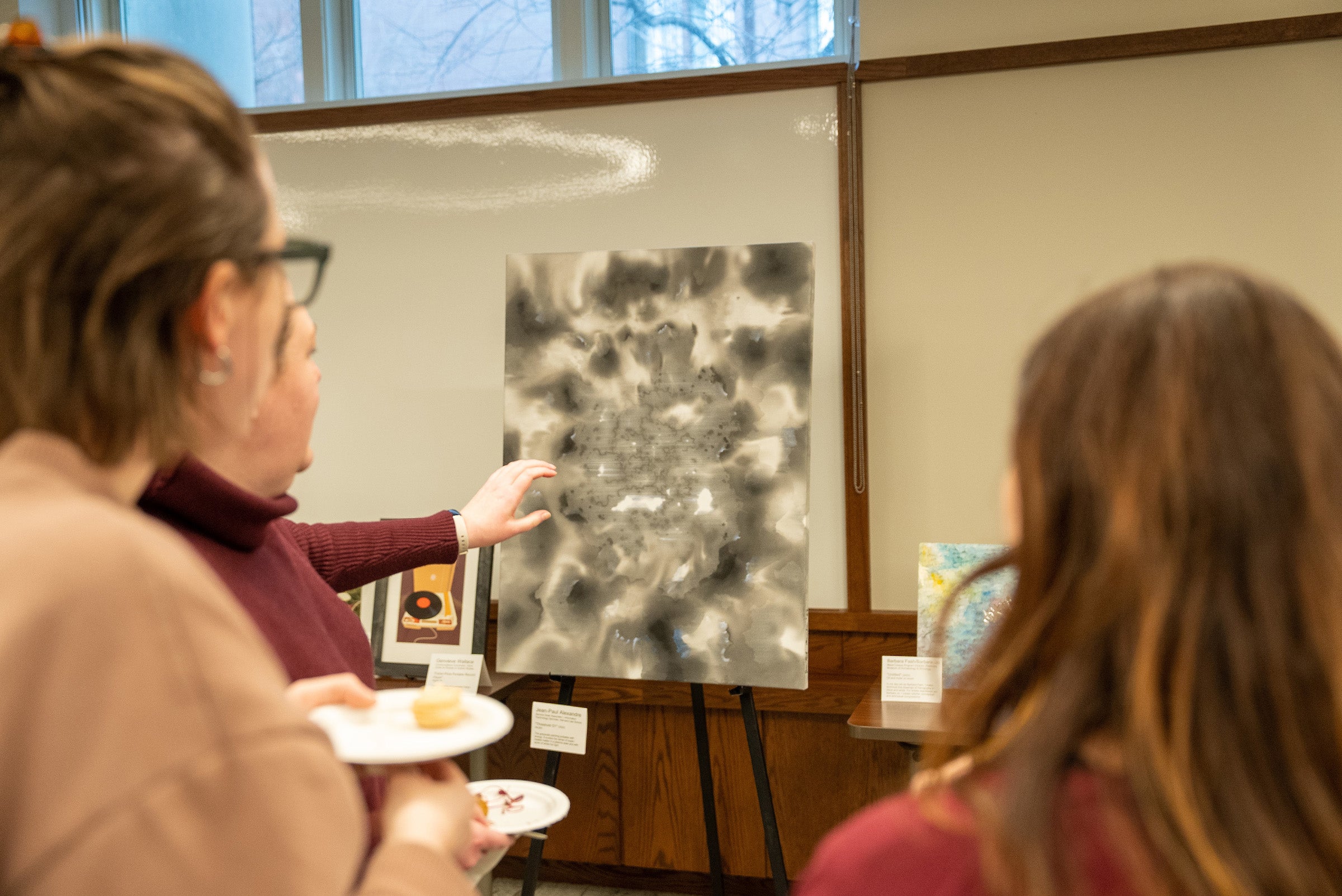 Women view greyscale painting.