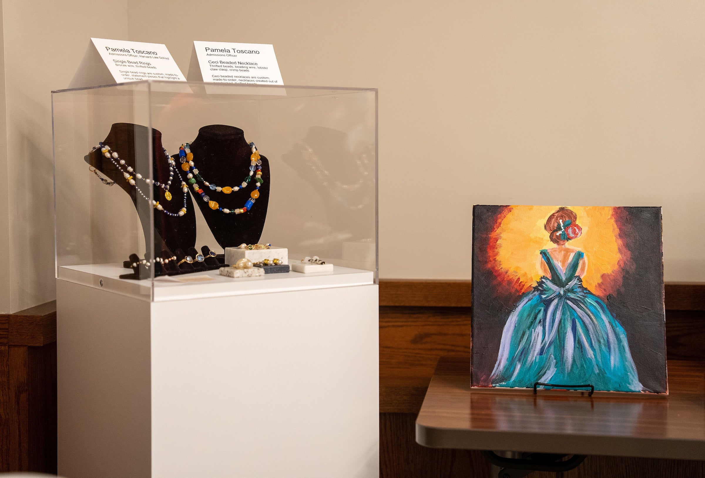 Painting of woman facing spotlight next to a display of necklaces and other jewelry.