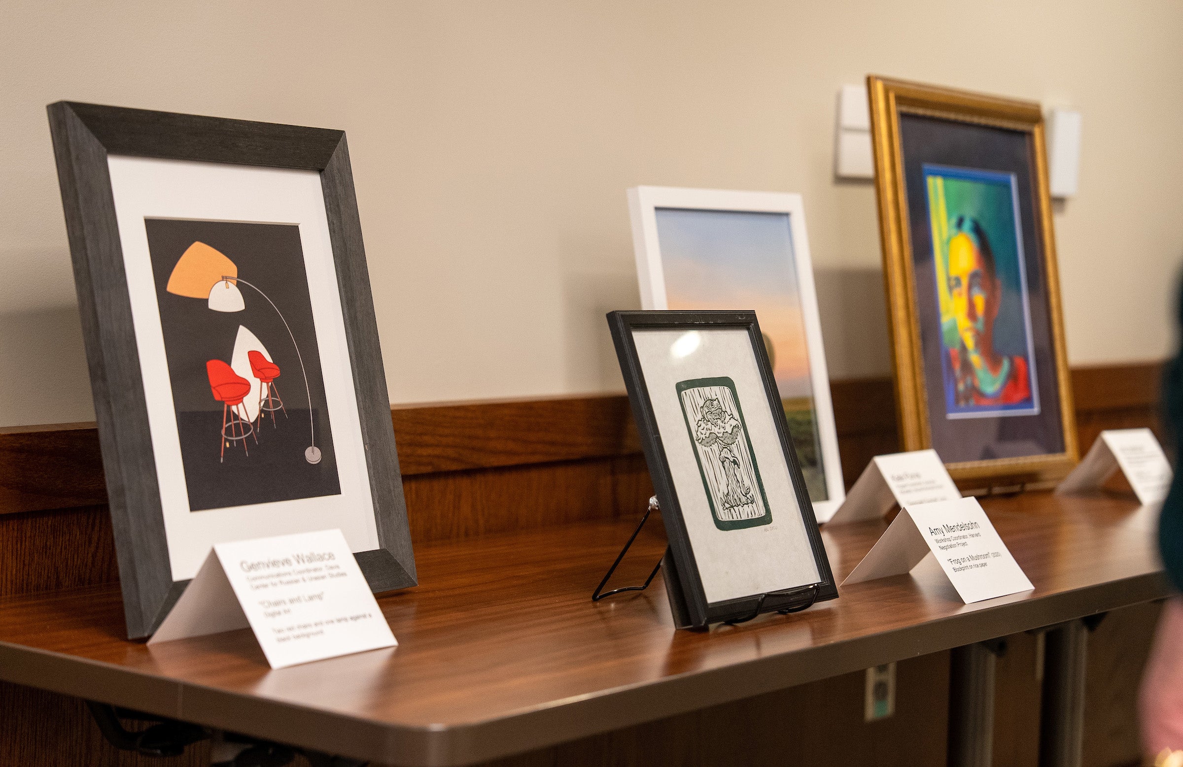 Display of four framed works of art on a table.