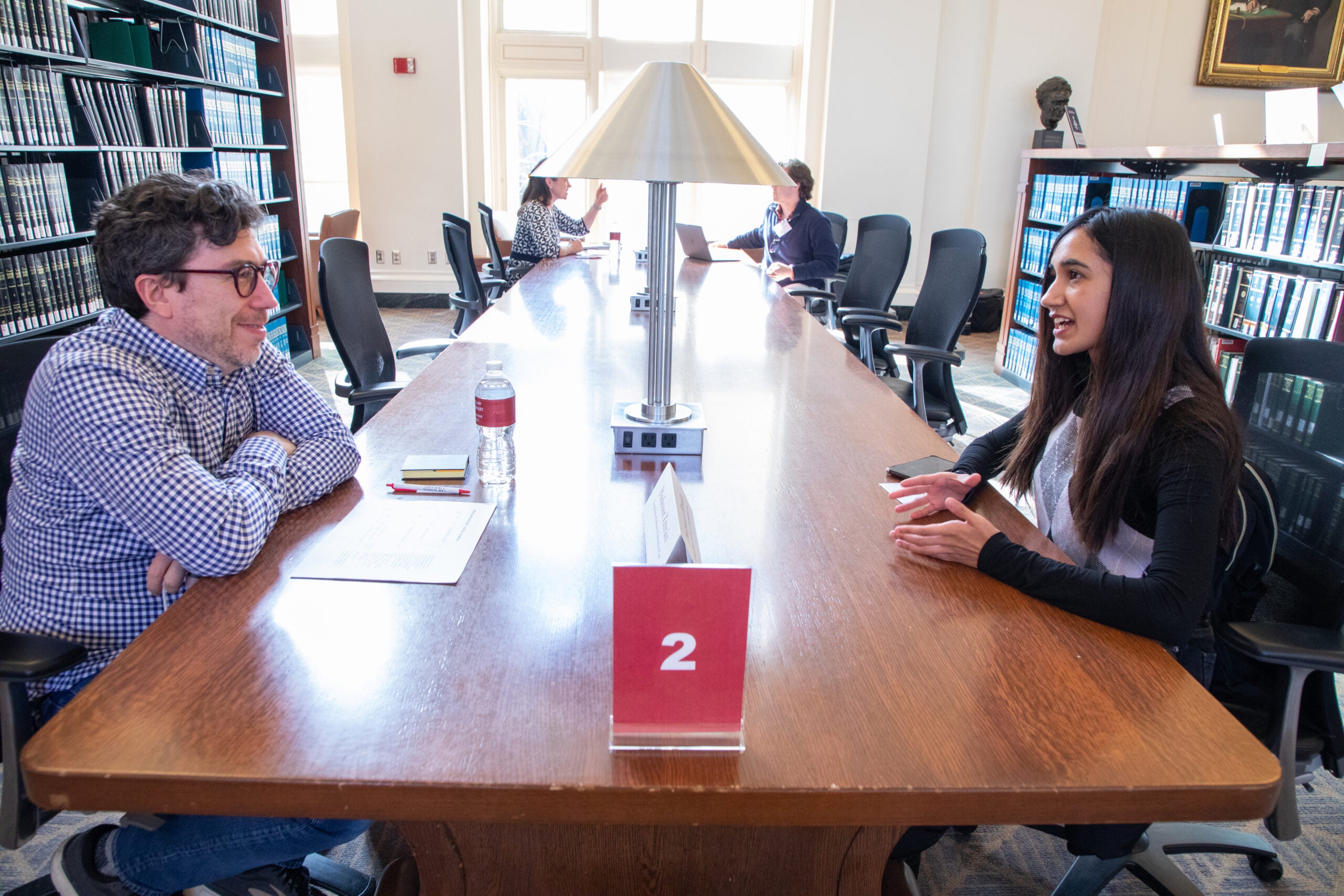 Two people at a table conversing in a library
