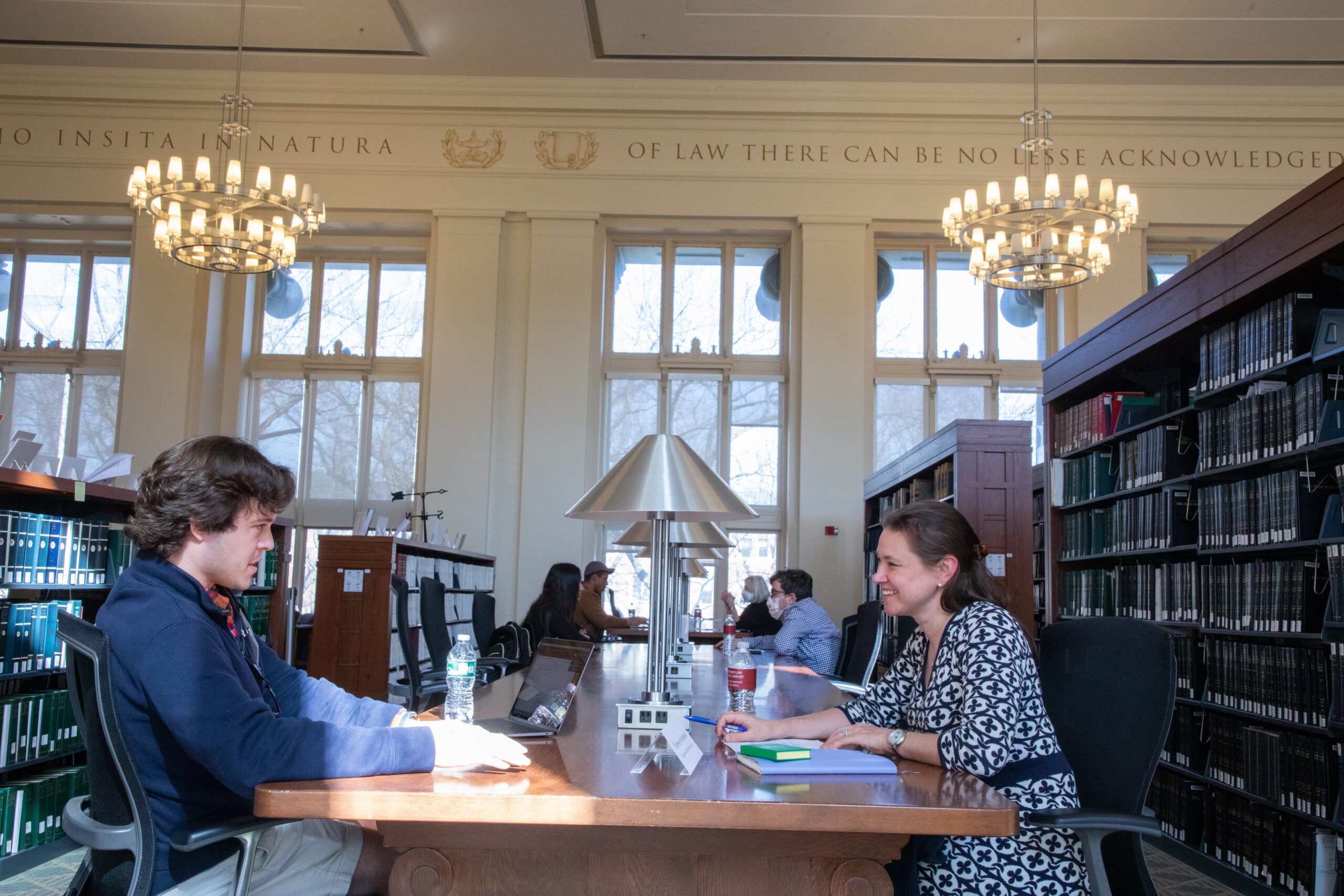 Two people conversing at a table in the library