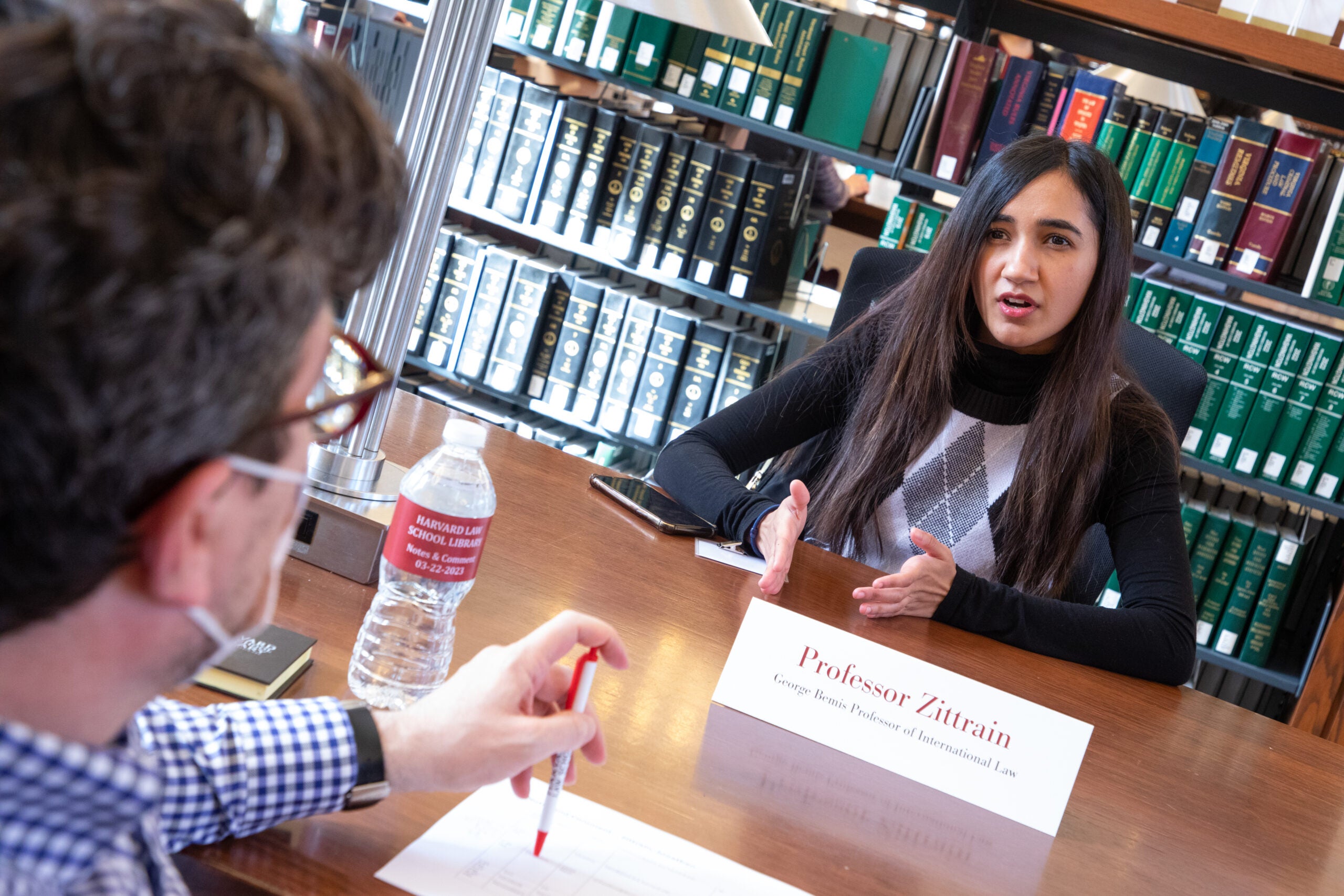 Two people speaking at a table in the library