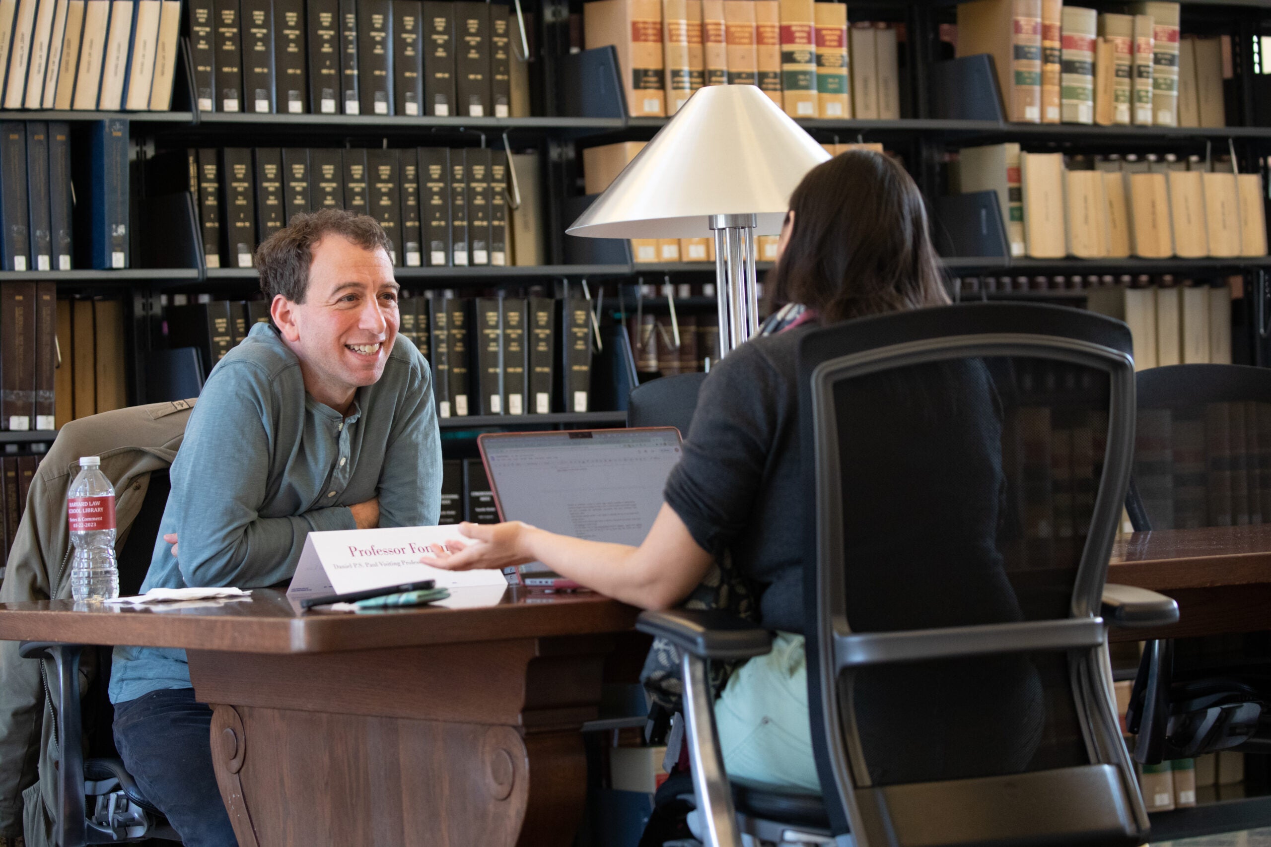 Two people talking at a table in the library