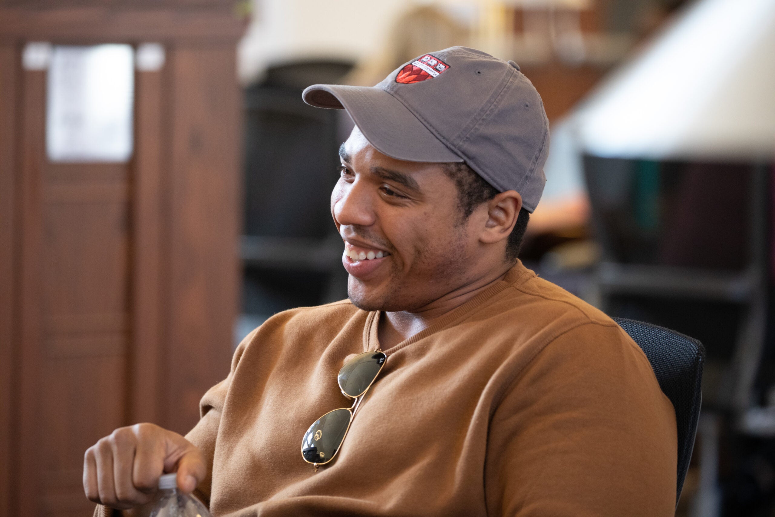 A man sitting at a table wearing a cap and smiling