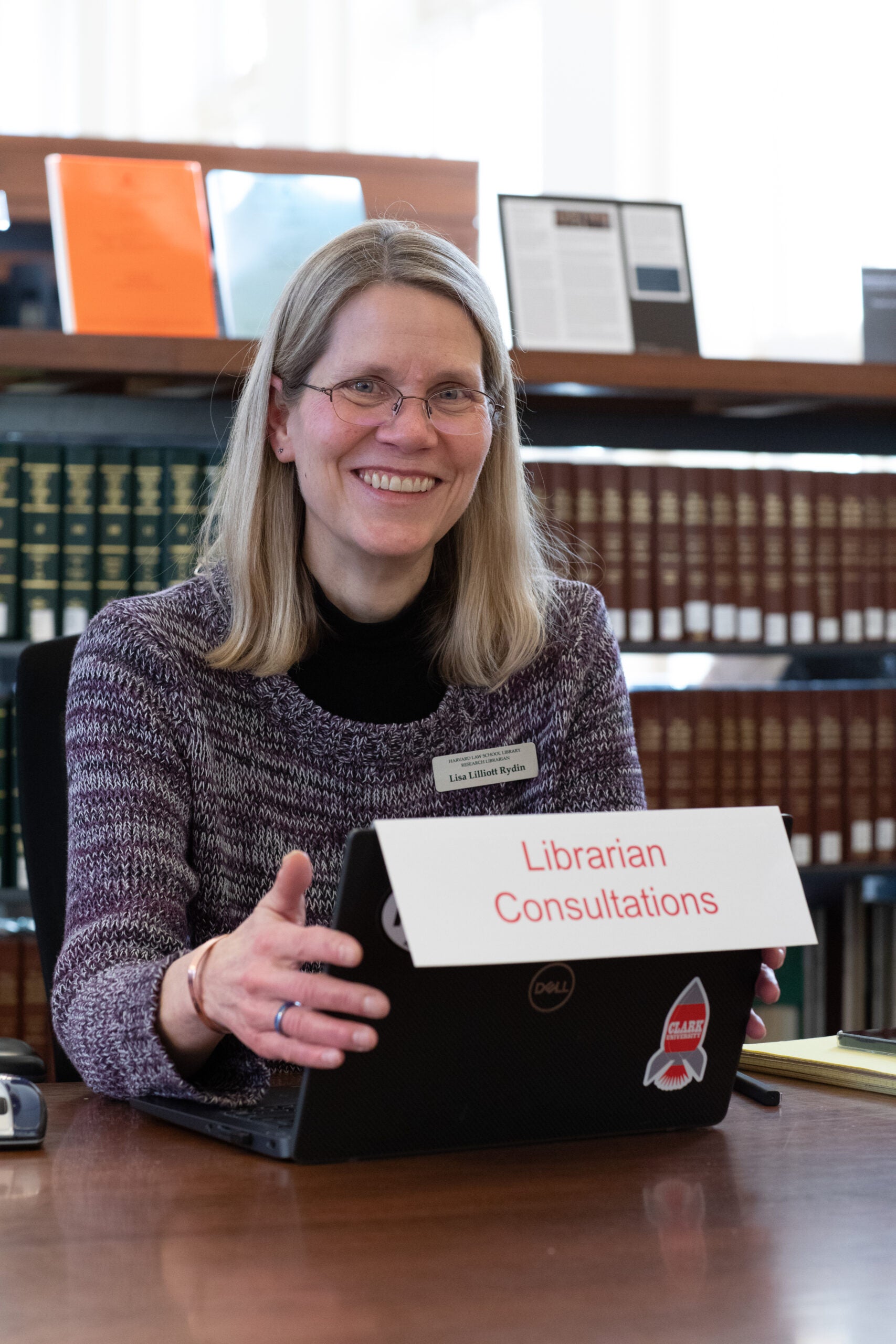 A woman sitting at a computer with the sign 