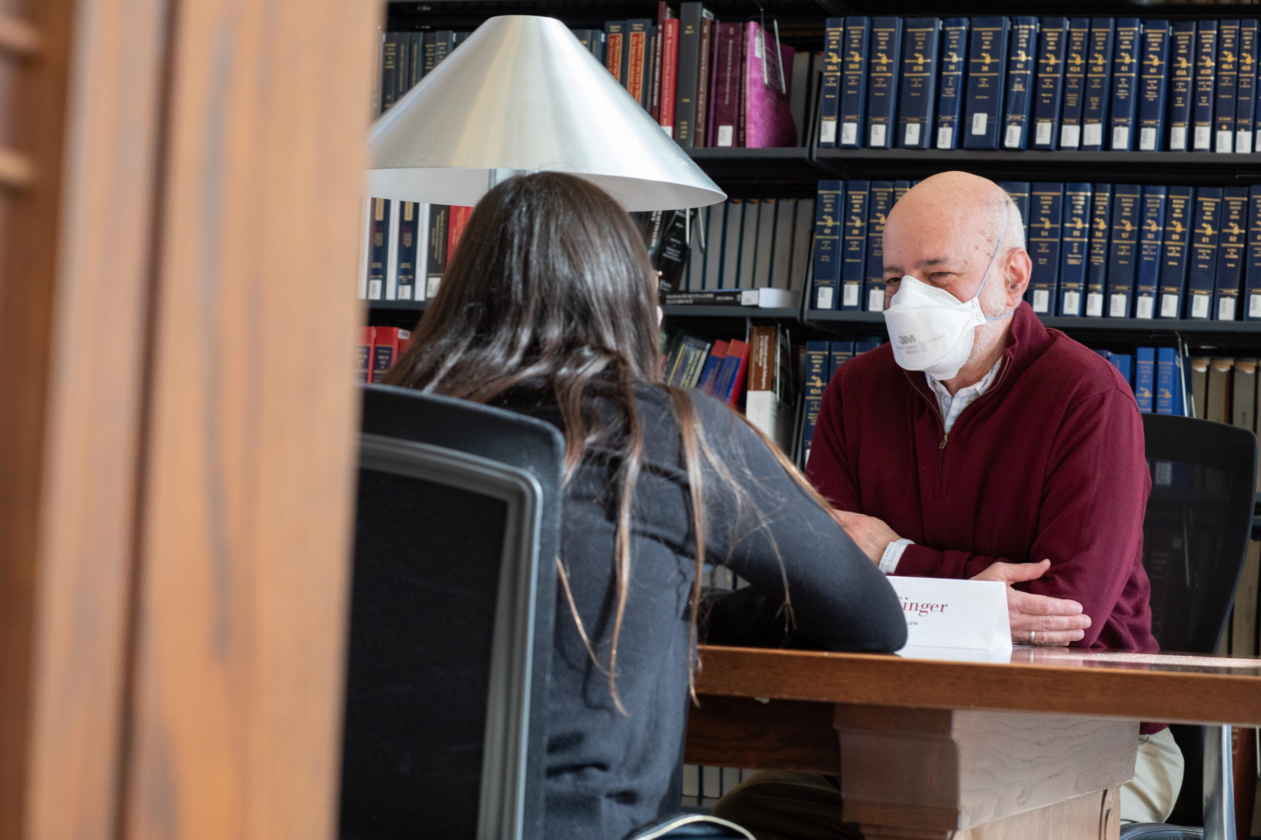 Two people at a table in a library talking